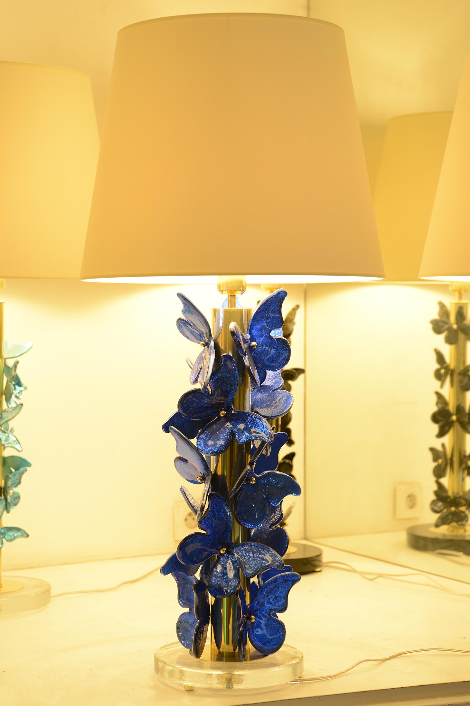 Lámpara de mesa Murano Mariposas azules con pulido
lámpara de mesa con base de latón cepillado ornamentada con azul oscuro
mariposas de cristal de murano con pan de plata tomadas bajo el murano 
de cristal. Con pantalla blanca (ligeramente crema)