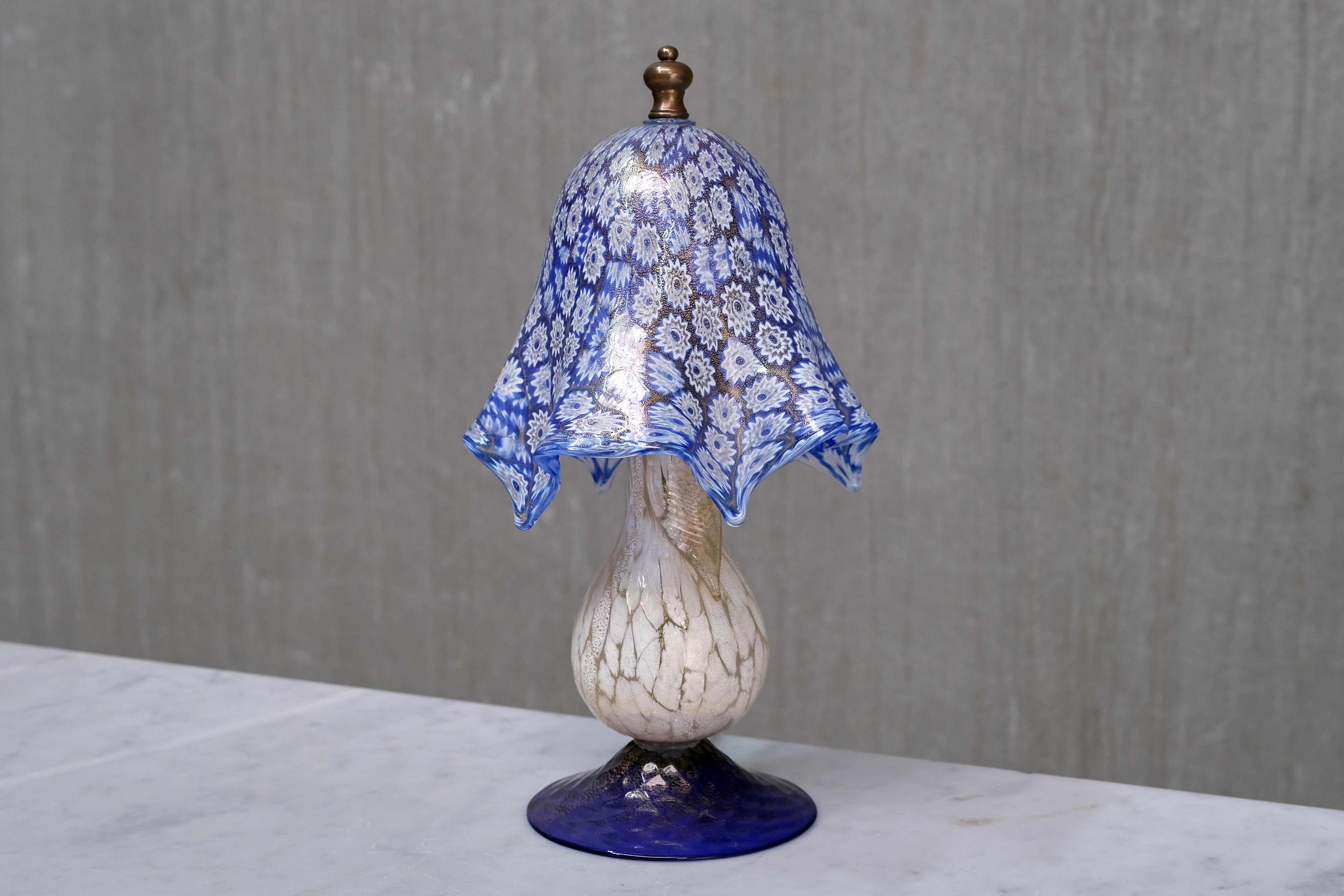 Esta lámpara de mesa bijou de Murano se fabricó en Italia en la década de 1970 y muestra una artesanía excepcional del cristal veneciano. La pantalla está realizada en vívido cristal millefiori azul y blanco, compuesto por innumerables cañas de