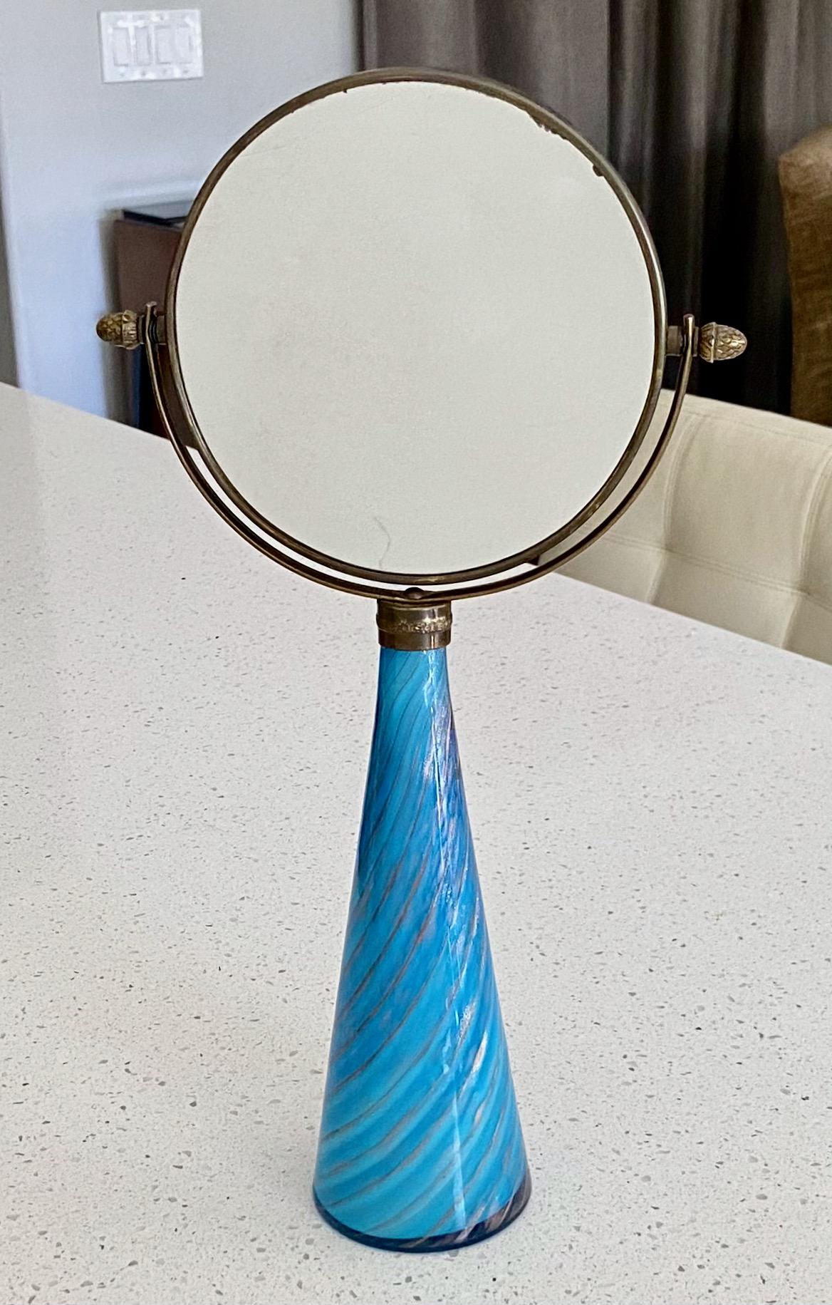 Smaller scale Murano vanity table mirror with cone shape blue and aventurine gold stripe hand blown glass base, top is a round 2 sided swivel brass mirror. The brass has a nice warm aged patina. The mirror portion is 5