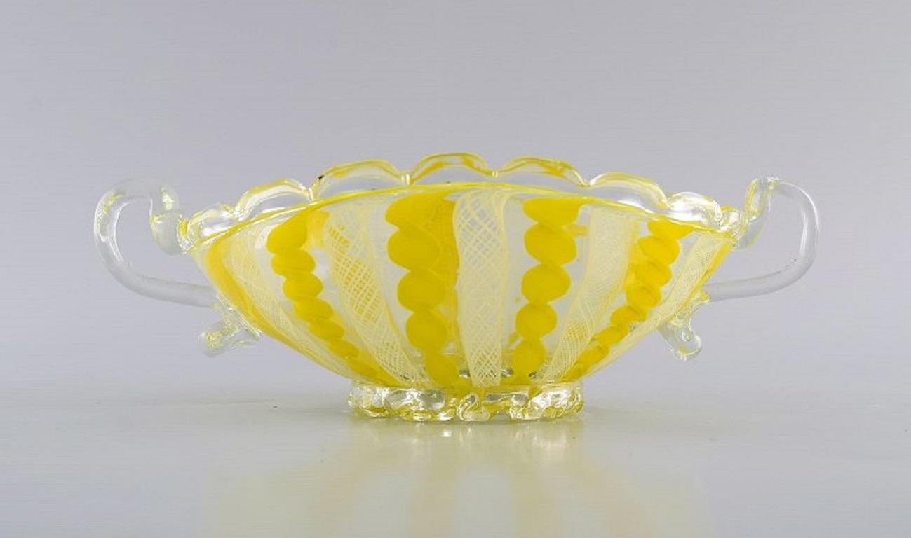 Bol de Murano avec poignées en verre d'art soufflé à la bouche. 
Motif ondulé et à carreaux dans des tons de jaune et de blanc. 1960s.
Mesures : 22.5 x 12 x 7,5 cm.
En parfait état.