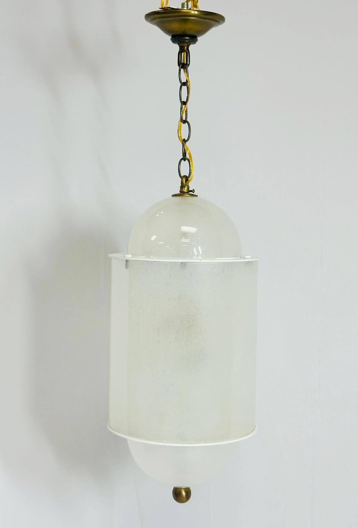 Eleva il tuo spazio con questa squisita lanterna di Murano e ottone, realizzata in Italia negli anni '60. Questo splendido apparecchio a sospensione è caratterizzato da un delicato paralume in vetro bianco sospeso da una catena in ottone, che emana