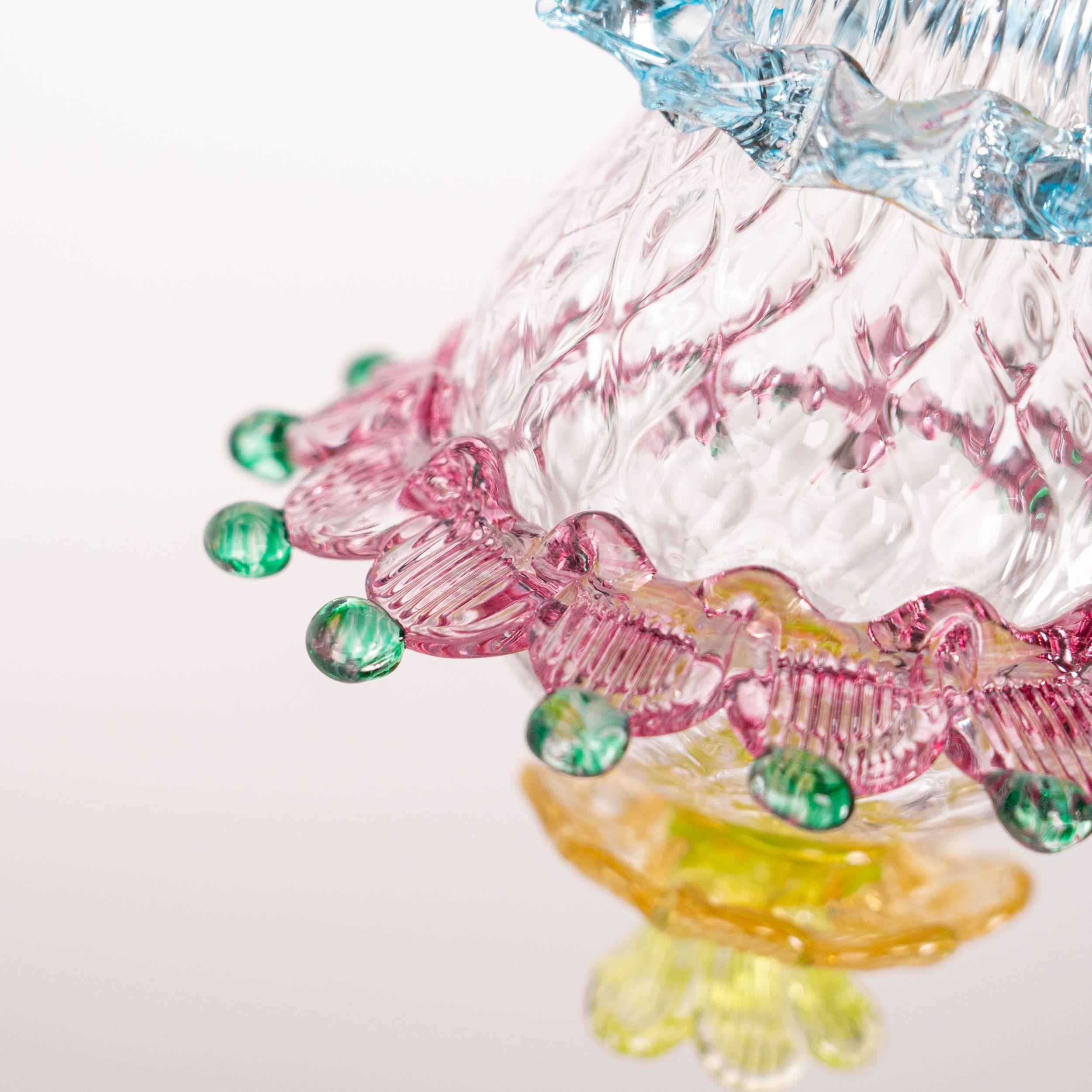 Blown glass body worked in balloton is decorated with evocative and original colors and shapes from the Murano craft tradition. The central body is surrounded by a rostral decoration in light blue glass, a ruby-colored morrisa with pulled pincers
