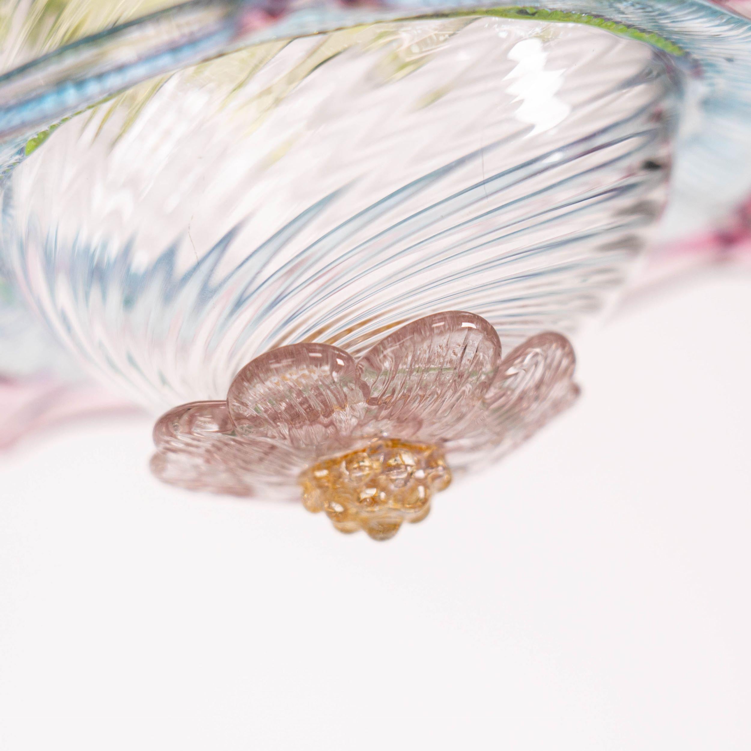 Le corps en verre soufflé travaillé en &Tradition est décoré de couleurs et de formes évocatrices et originales issues de la tradition artisanale de Murano. Le corps central est entouré de décorations de saupoudrage en verre vert acide, bleu clair