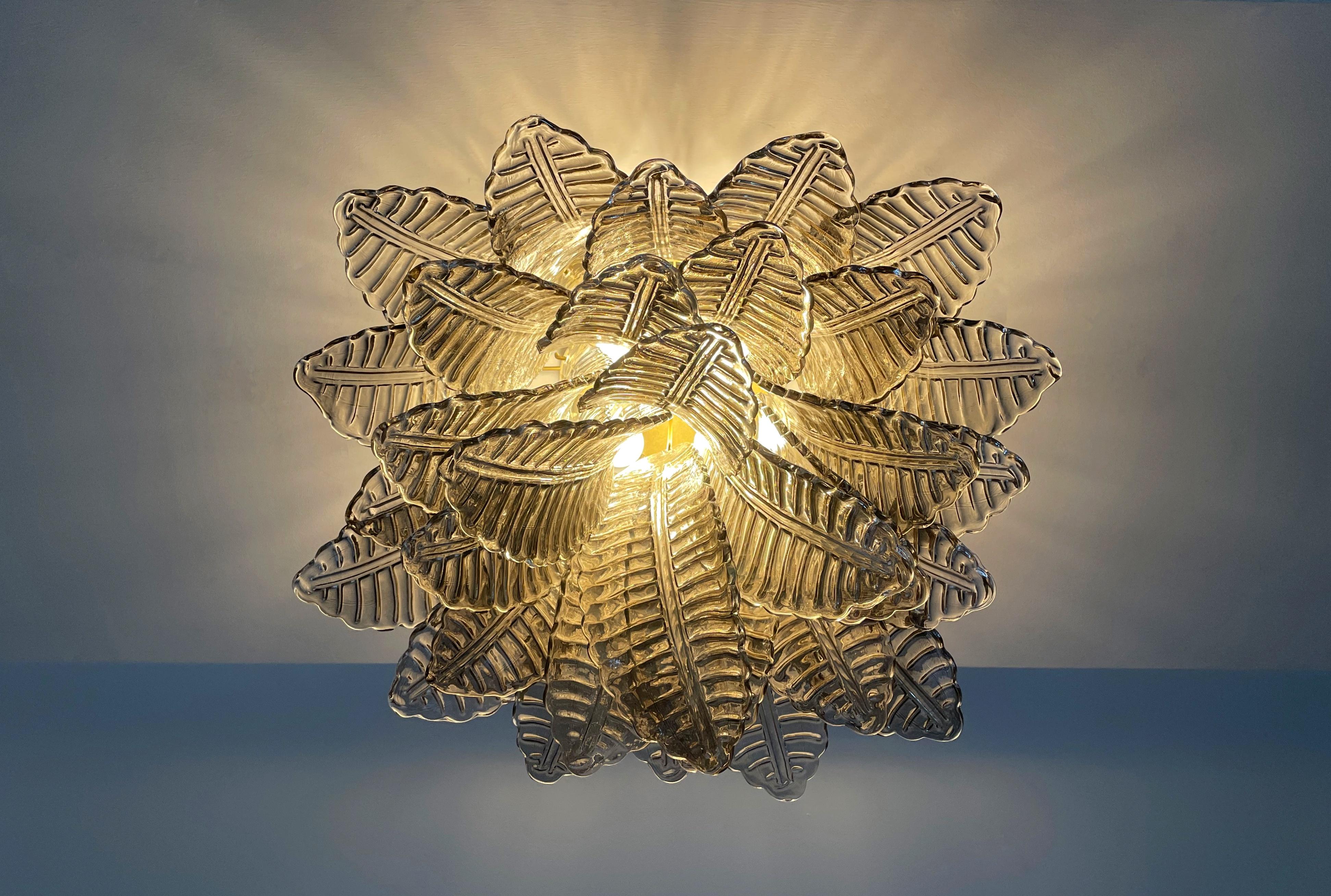 Espectacular lámpara de techo
p con 32 hojas ahumadas de Murano en marco de metal pintado dorado.  Elegante objeto luminoso.
Periodo: finales del siglo XX
Dimensiones: 45 cm de alto; 55 cm de ancho; 55 cm de fondo.
Dimensiones de las gafas: 33 cm de