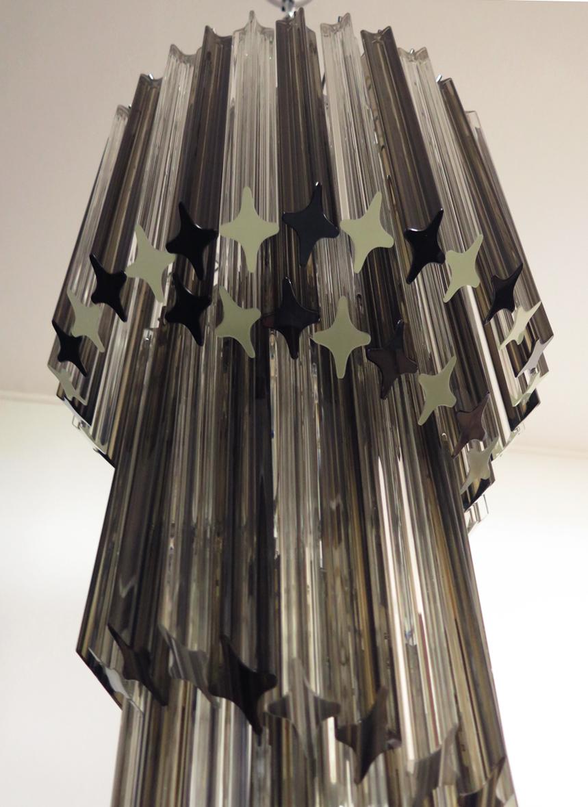 Fantastischer Vintage-Kronleuchter aus 86 Murano-Kristallen mit transparentem und geräuchertem Prisma in einem Rahmen aus vernickeltem Metall. Die Form dieses Kronleuchters ist spiralförmig.
Zeitraum: Ende des 20. Jahrhunderts
Abmessungen: 63 Zoll