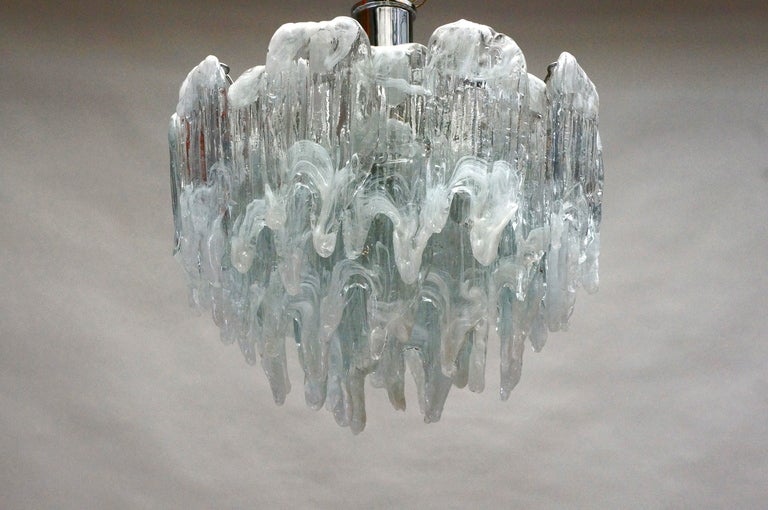 A vintage Italian chandelier composed of 34 frosted Murano glass parts, Italy.
Form shader suspended from a chrome frame.