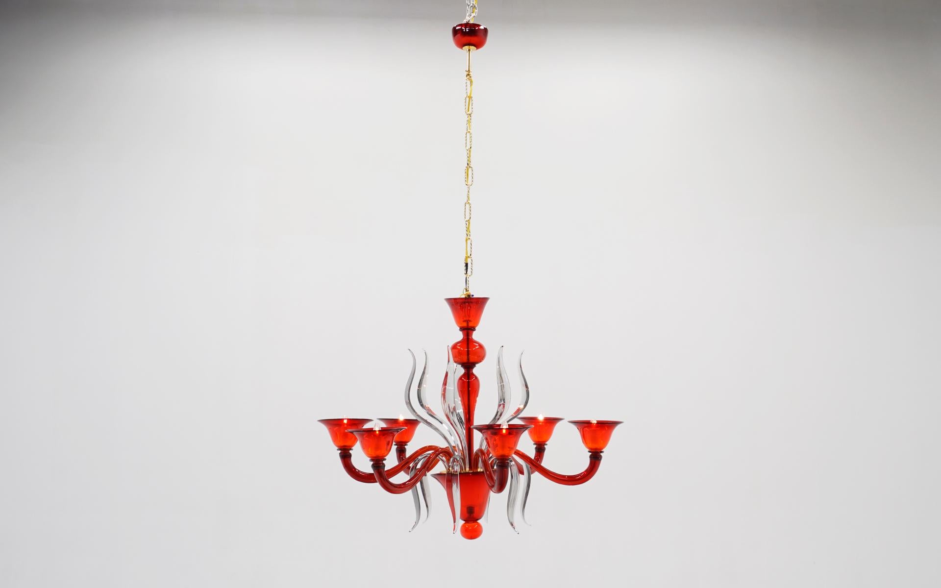 Exceptional vintage murano blown glass six light chandelier in red and clear art glass. The clear glass pieces simply insert into the center and the shades are removable for shipping. This also retains the red art glass canopy that connects the the