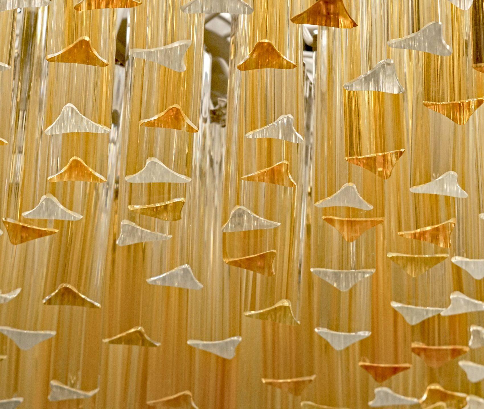This chandelier has about 300 elements of triedri elements. There is a combination of clear and amber ones, to give a soft tone but not trapping the light too much. A stunning mosaic effect created by the polished ends. Lower session is cone shaped