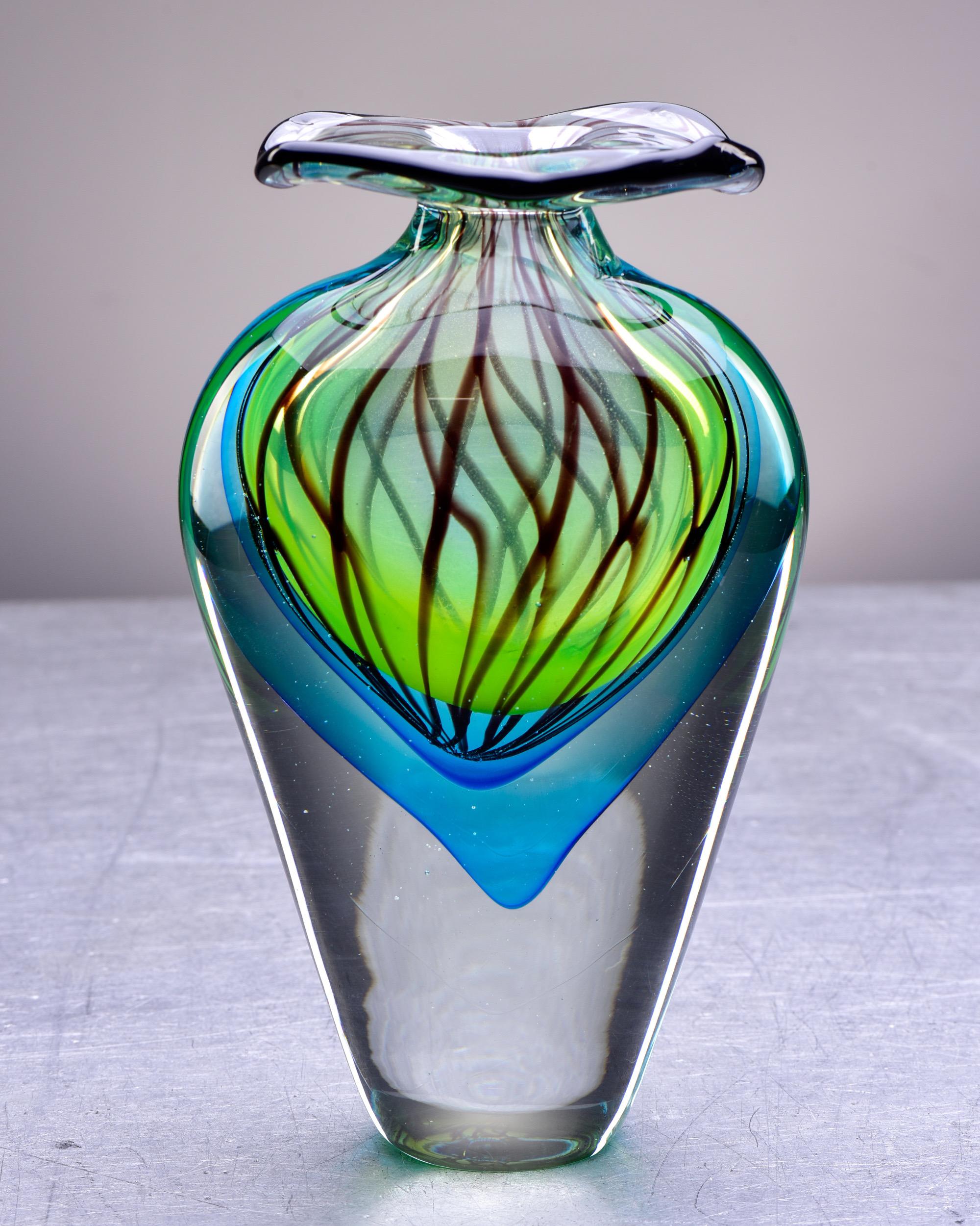 Circa 1990s tall Murano glass vase in sommerso style with heavy, clear glass base with layers of blue and green, dark swirls and a wide, flared lip. Unsigned. Underside of base shows some scratches - see detail photo.