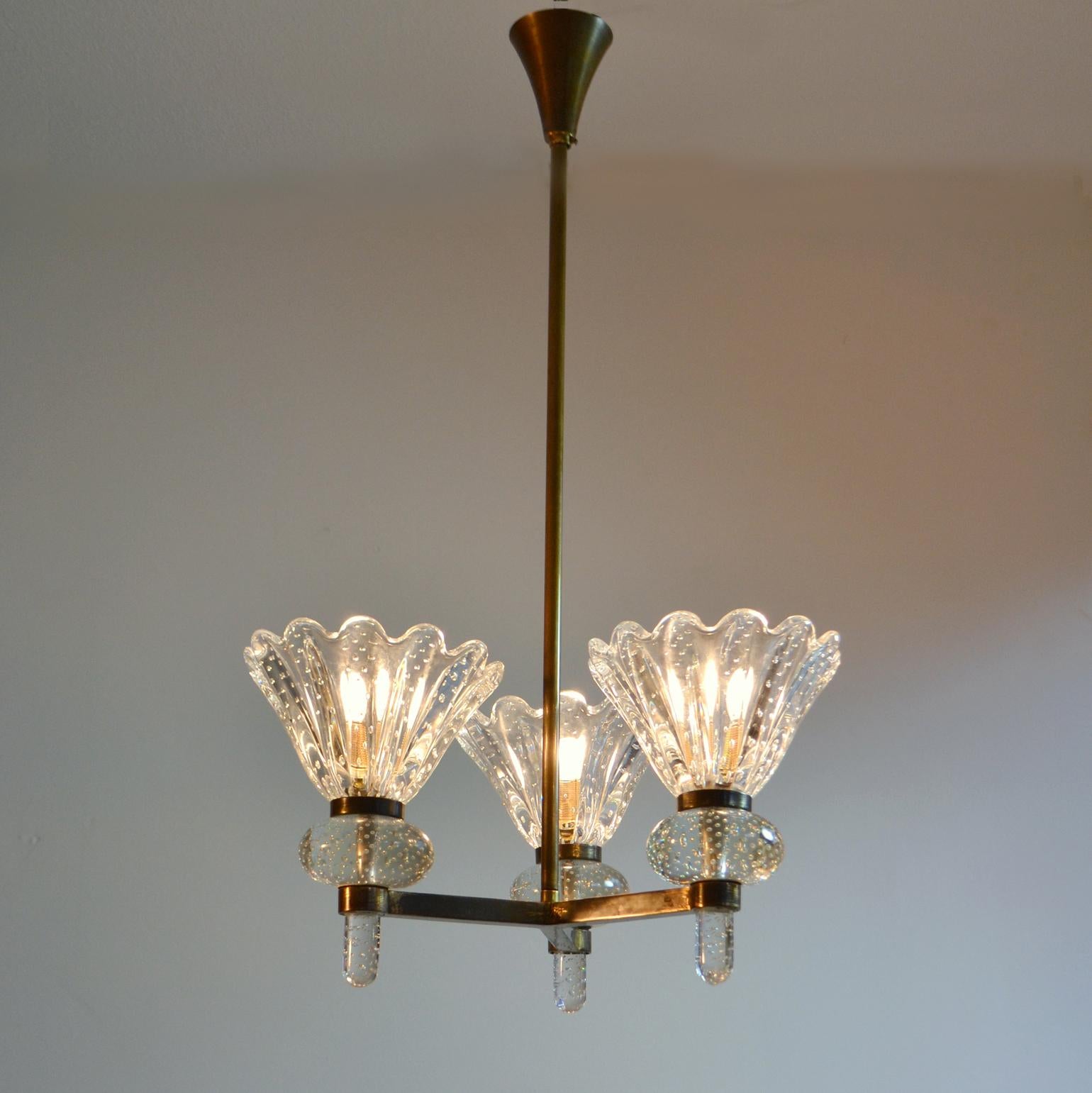 Murano Pulegos glass three arm chandelier on brass frame creates fountain of the light. The clear glass scalloped shades of this elaborate lamp are mouth-blown and rest like torches in the brass frame. Barovier & Toso Murano Murano glass and brass