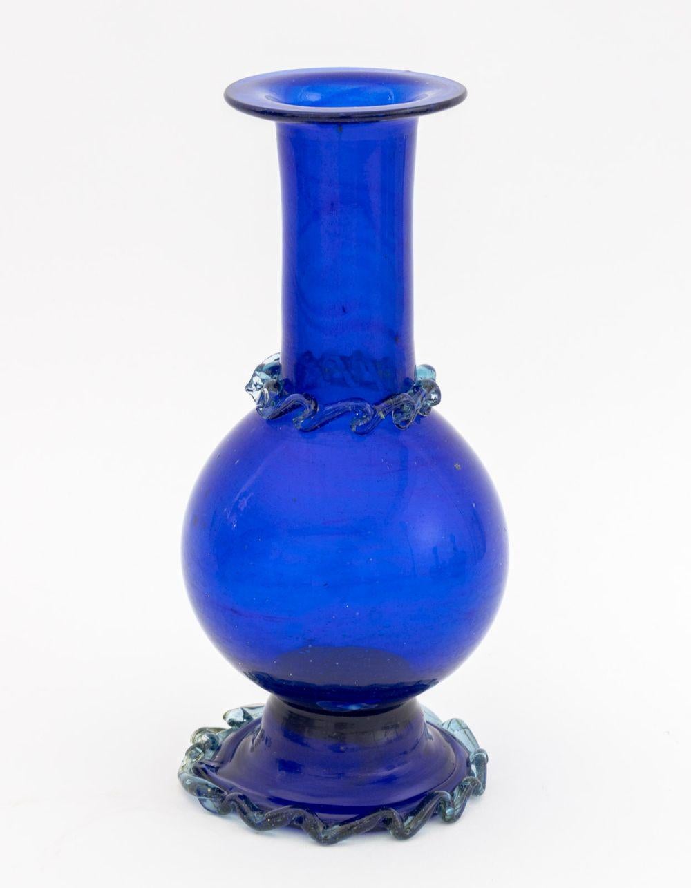 Gruppe von vier kobaltblauen Murano-Glasartikeln, bestehend aus: einer goldglänzenden Glasvase, einer Balustervase mit aufgesetzten türkisfarbenen Glasakzenten, einer zylindrischen kannelierten Vase und einem überdachten Gefäß.

Größte: 10,5