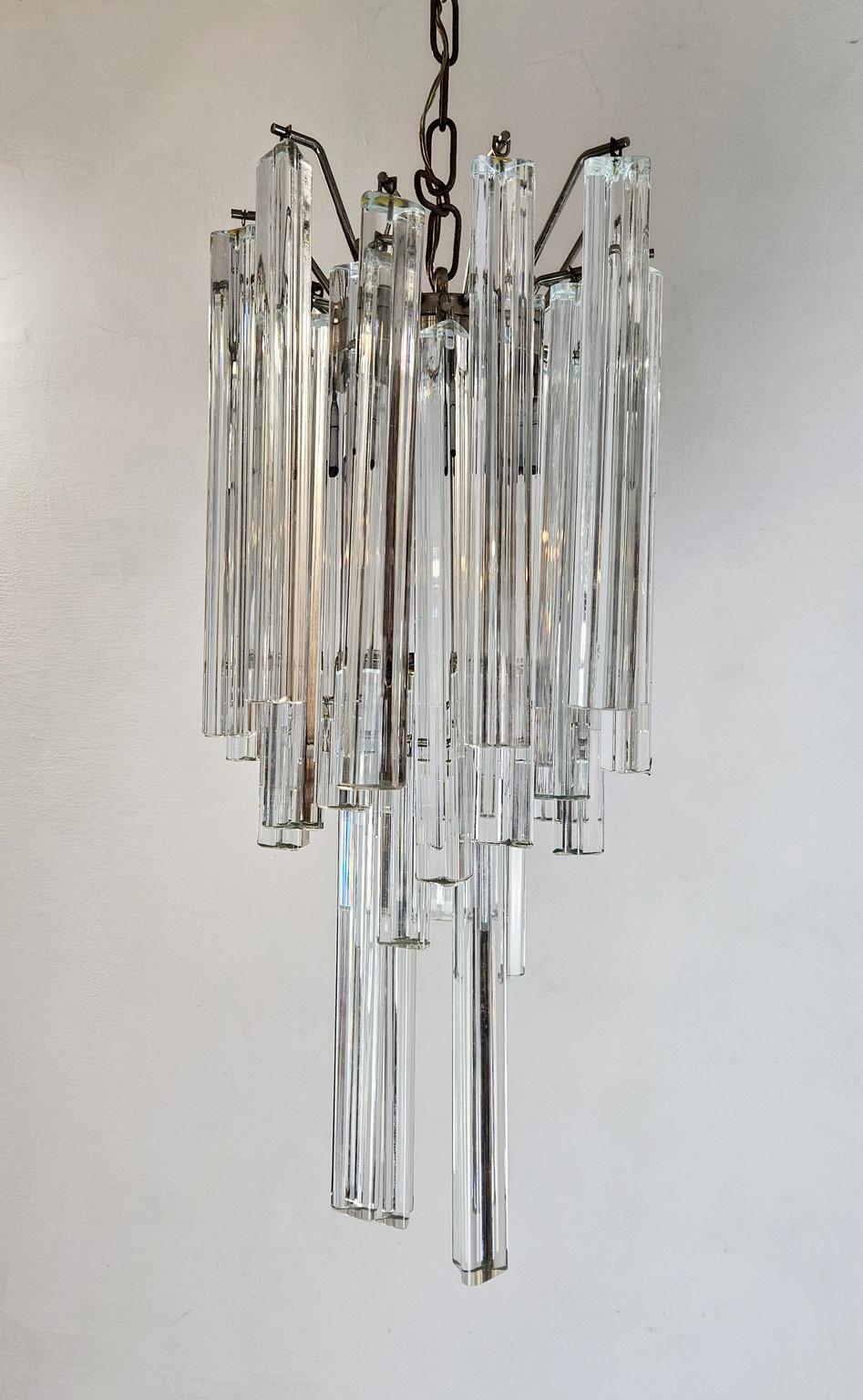 Ein sogenannter Tryri-Kronleuchter aus Kristall, hergestellt von Venini, Murano. Die Kristalle sind klar und hängen stufenweise an einem verchromten Stahlsockel. Verleiht dem Raum herrliches Licht und Reflexionen. Die Struktur ist 60 cm hoch und die