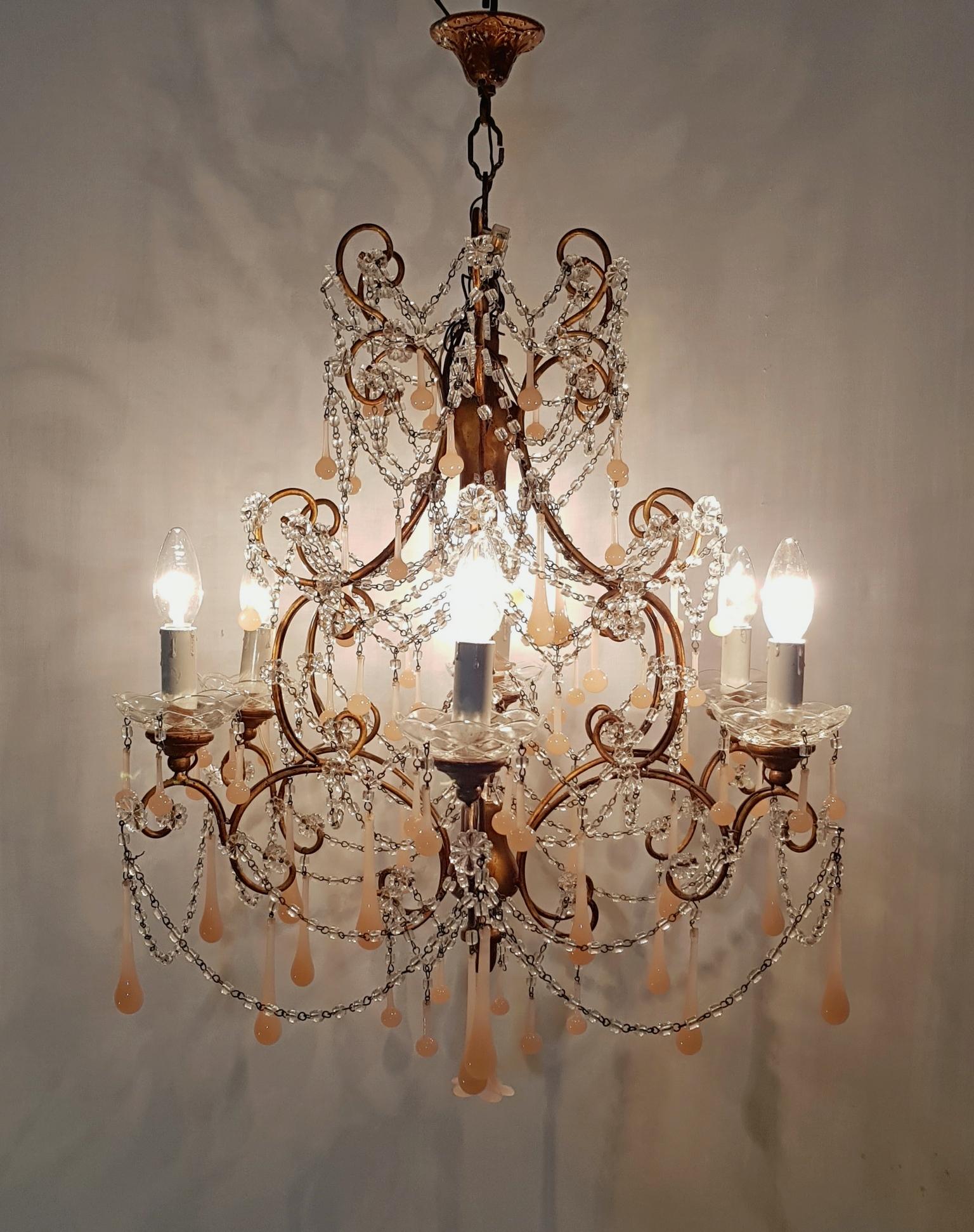 This gorgeous and complete handmade Murano chandelier houses six lights sitting with long light pink opaline Murano crystals and swags of clear macaroni beads featured on a giltwood top, centre and posts. Rewired and ready to hang. Wiring compatible