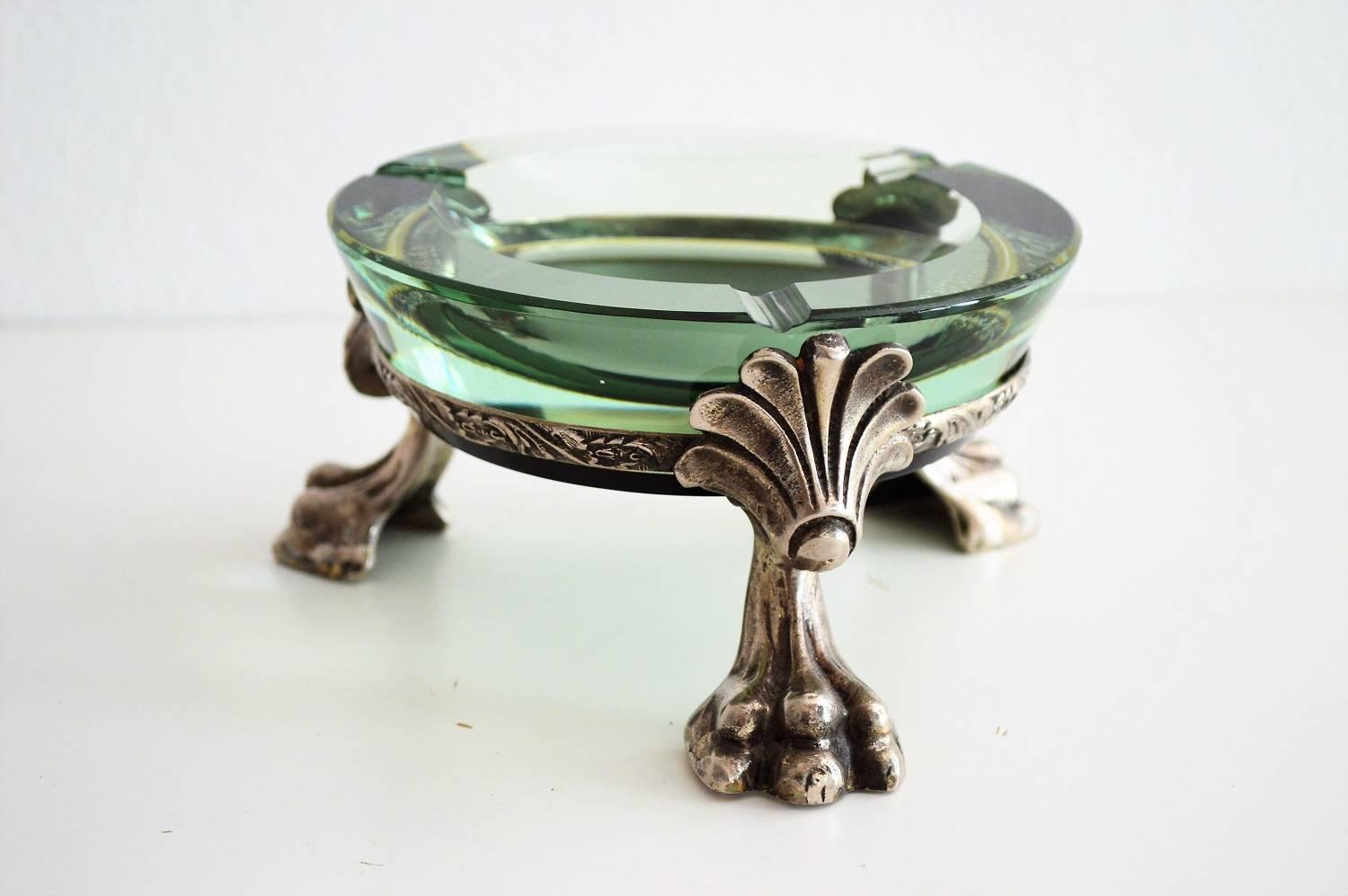 Gorgeous ashtray in dark green color with yellow inclusion made of crystal glass.
The glass is hold by a metal holder with three lion paws in the neo-renaissance style.
Beautiful piece in excellent condition.
 