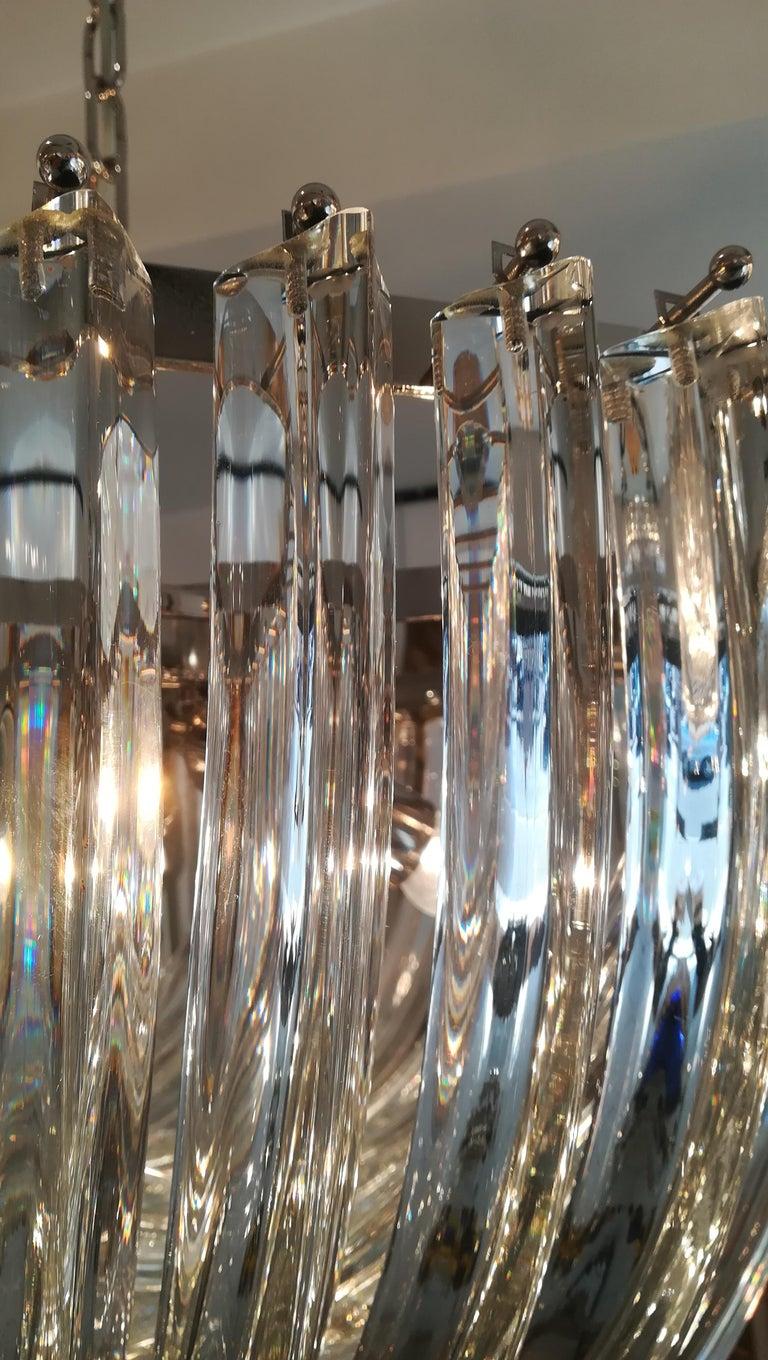 Murano mundgeblasener Kronleuchter aus klarem Kristallglas.

Halterung aus verchromtem Stahl.
Maße: Durchmesser 60 cm
Fünf Glühbirnen E27
Maße: Die Höhe (40 cm) gilt nur für den Korb.
Die Gesamthöhe von 100 cm kann reduziert oder erhöht werden.
 