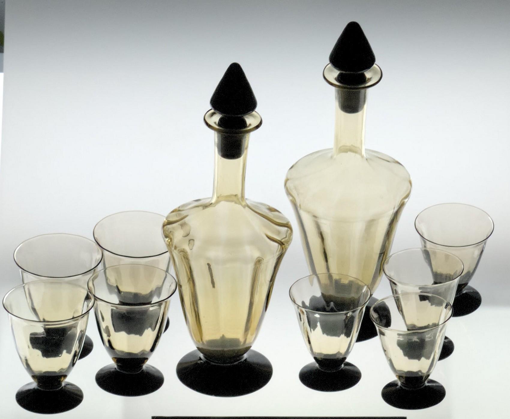 A port or cherry set made of two bottles (white and red) with stopper. Body is in fume rigadin and black foot. 4 larger glass and 4 smaller glass. Probably in origin was a white and red wine set. 

Glass shows fume glass typical color variation