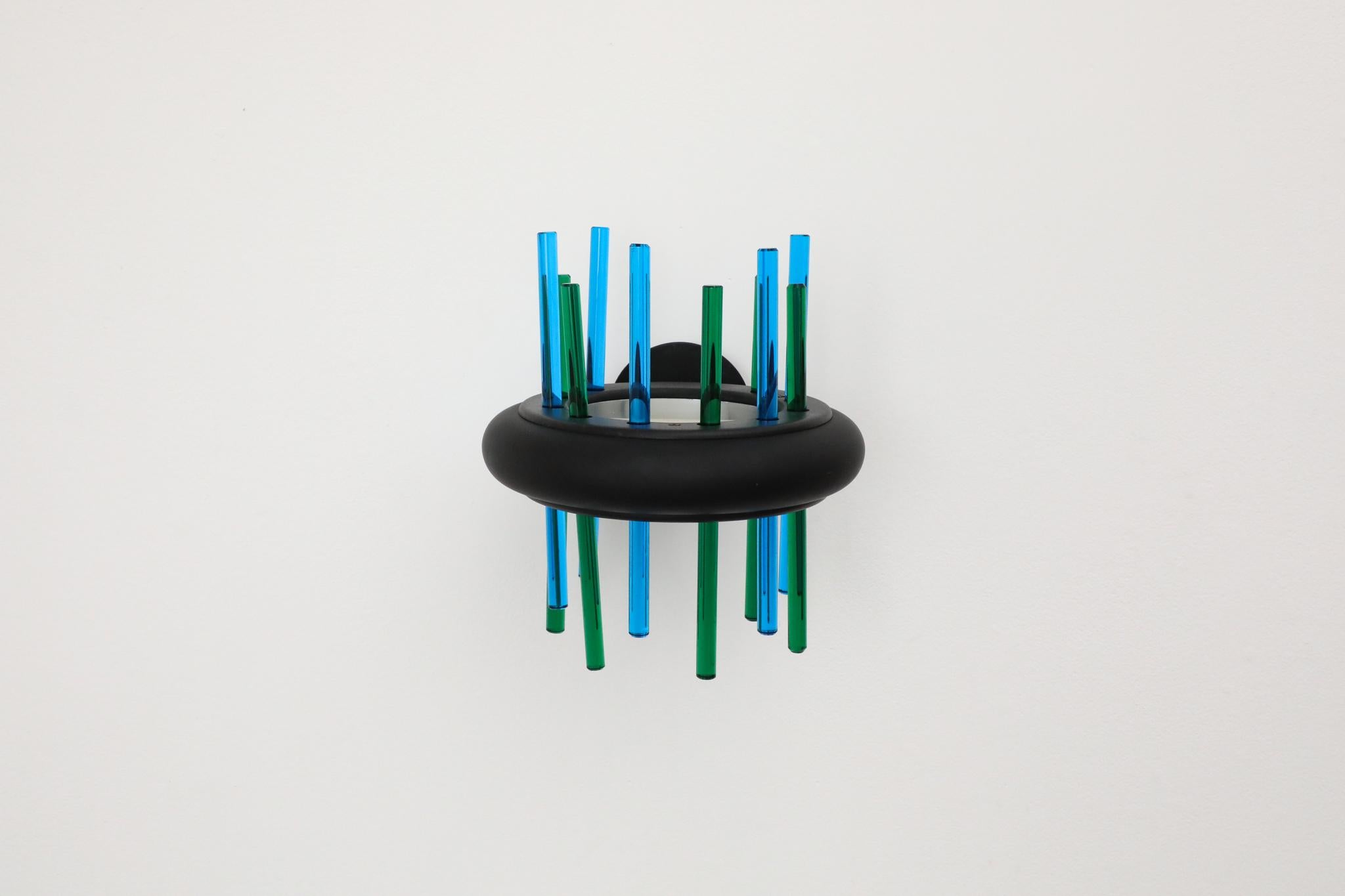 Un llamativo aplique italiano de Murano Due de la década de 1980, que muestra el arte del cristal de Murano. Esta lámpara presenta unas esculturales varillas de cristal dispuestas verticalmente en vivos colores azul cobalto y verde esmeralda,