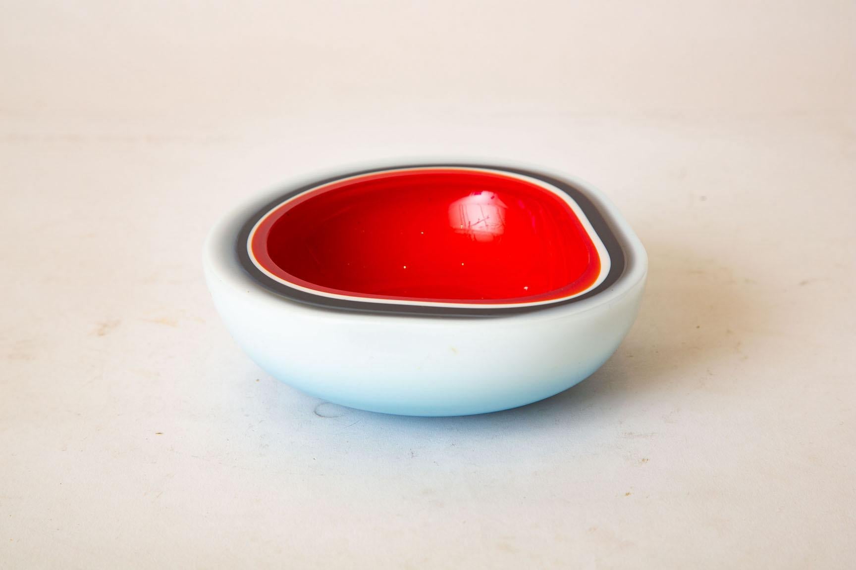 This wonderful vintage Italian Murano Flavio Poli triple cased glass bowl is unusual. It has white cased exterior, going into black glass line to a red interior. It is vintage from the 1960s. It is white cased with clear with a red interior and a
