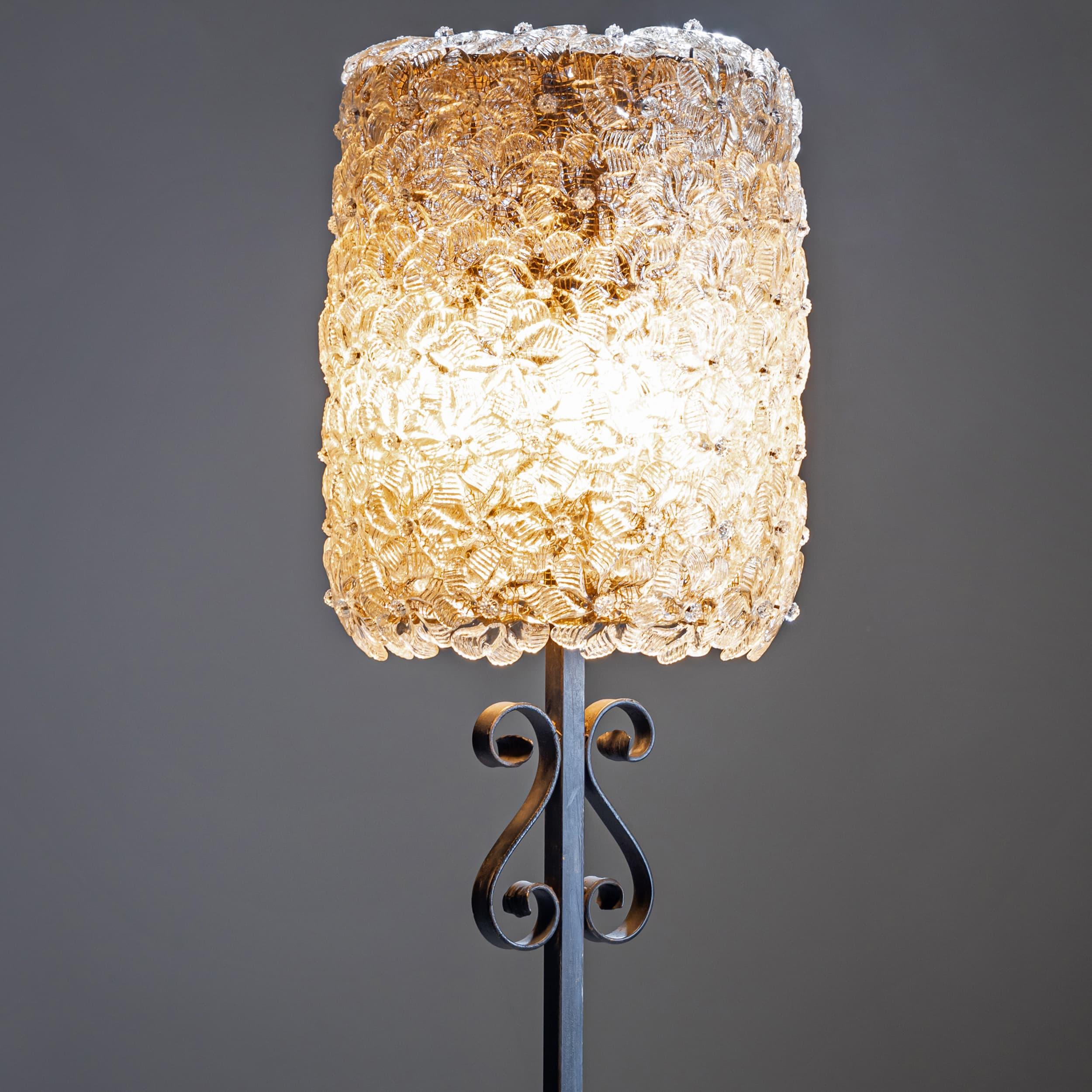 Elegant floor lamp on a decorative iron base with volute motifs. The cylindrical lampshade is composed of numerous individually crafted glass flowers featuring delicate gold shimmer inclusions. The piece is attributed to Barovier & Toso.