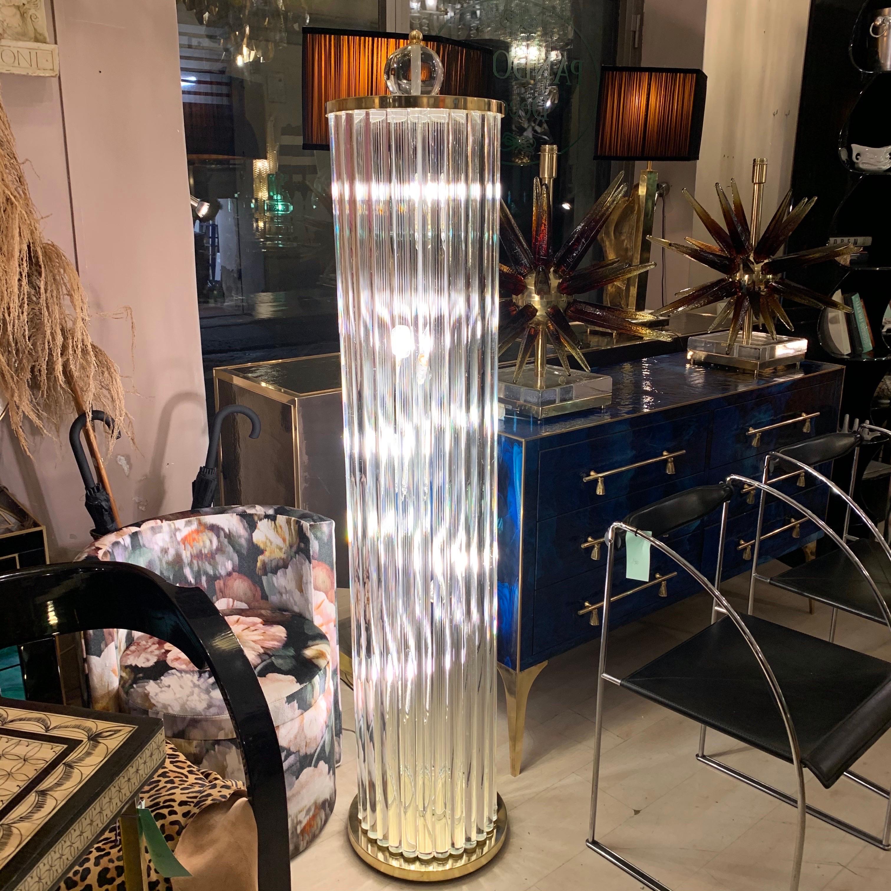 Lampadaire Murano avec tiges en verre clair, base et sommet en laiton. Le lampadaire est une sculpture en verre transparent en forme de colonne, sur le dessus se trouve une sphère en verre transparent de Murano. Lampes à cinq ampoules.
Peut être