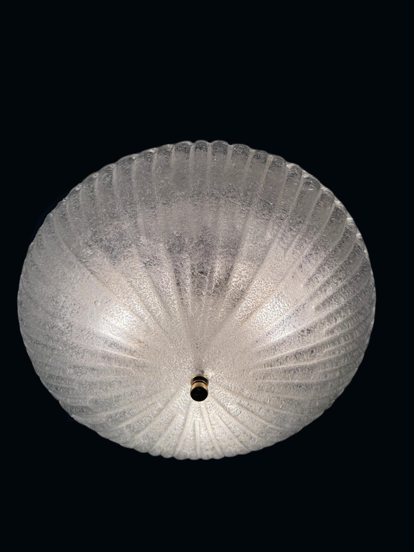 Questa squisita lampada da soffitto a incasso di Murano è un perfetto esempio di artigianato italiano e tedesco senza tempo. Realizzata in vetro di Murano di alta qualità, la lampada presenta un paralume in vetro splendidamente strutturato che