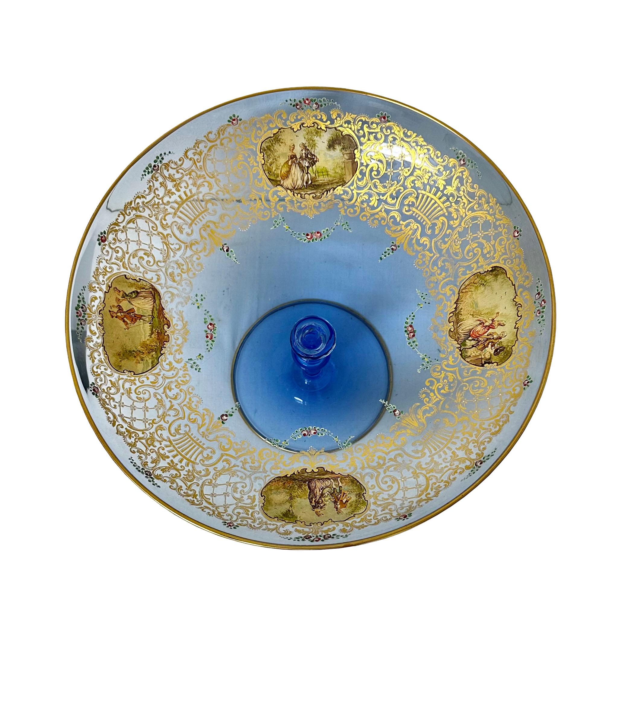 Magnifique coupe à fruits sur pied en bleu de Murano du début du siècle, avec dorures. Quatre figures peintes dans le cartouche. La dorure est parfaite. 