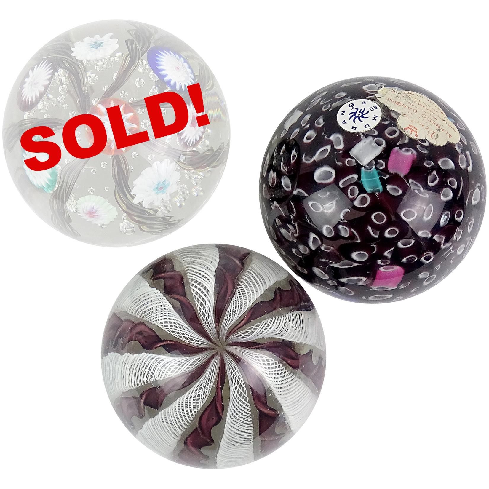 Priced per item (2 designs available, as shown). Beautiful vintage Murano hand blown Italian art glass paperweights. Documented to Fratelli Toso and Alfredo Barbini. The first is a dark purple / maroon with aventurine flecks and Zanfirico white