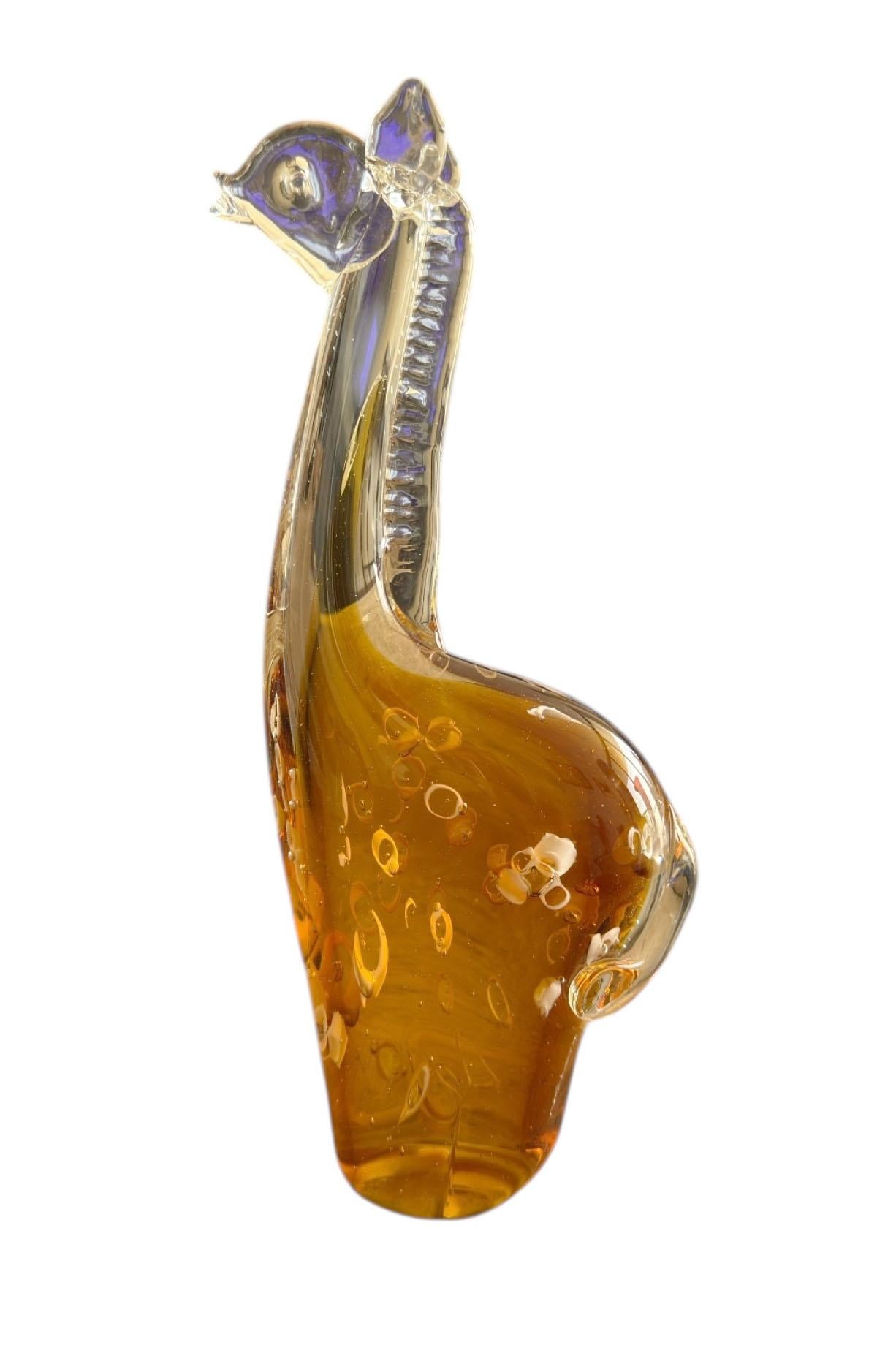 A whimsical and refined Murano glass giraffe figurine, handblown in Italy with exceptional attention to detail. The elongated neck and playful posture are brought to life through expertly swirled glass in warm amber and clear tones, capturing the