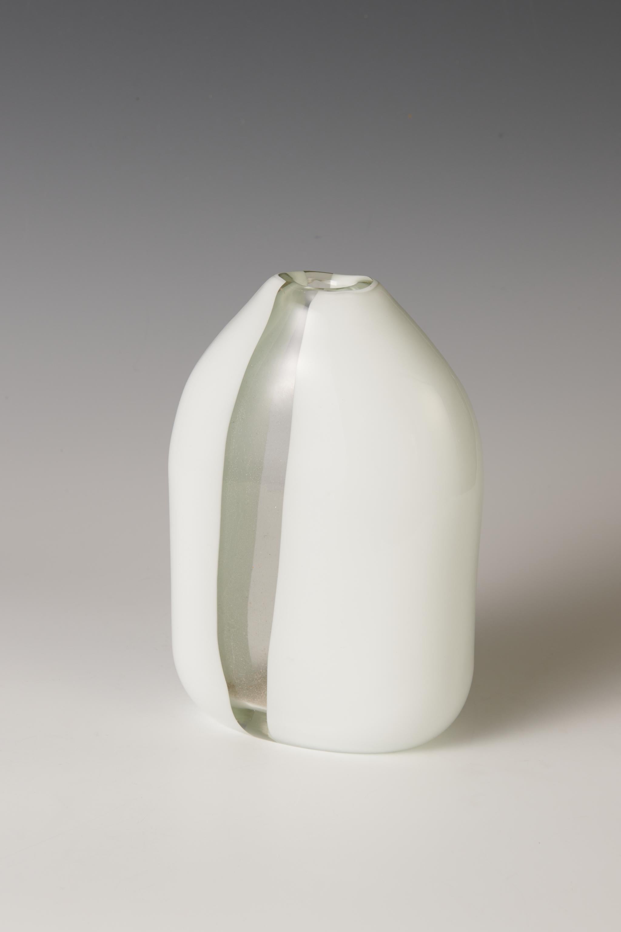 Un vaso in vetro lattimo sommerso con decorazione a fascia in cristallo. Vaso in vetro di Murano firmato. Vetro incolore con parte bianca opaca sovrapposta tra gli strati.Firmato / Marcato : Con firma 