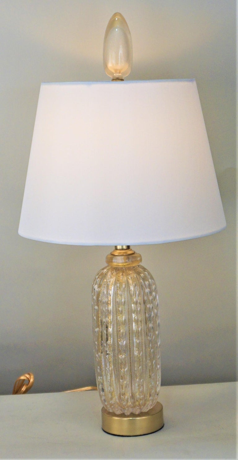 Clear blown glass with touch of gold or champagne color lamp with brass bas and fitted with hardback silk lampshade.