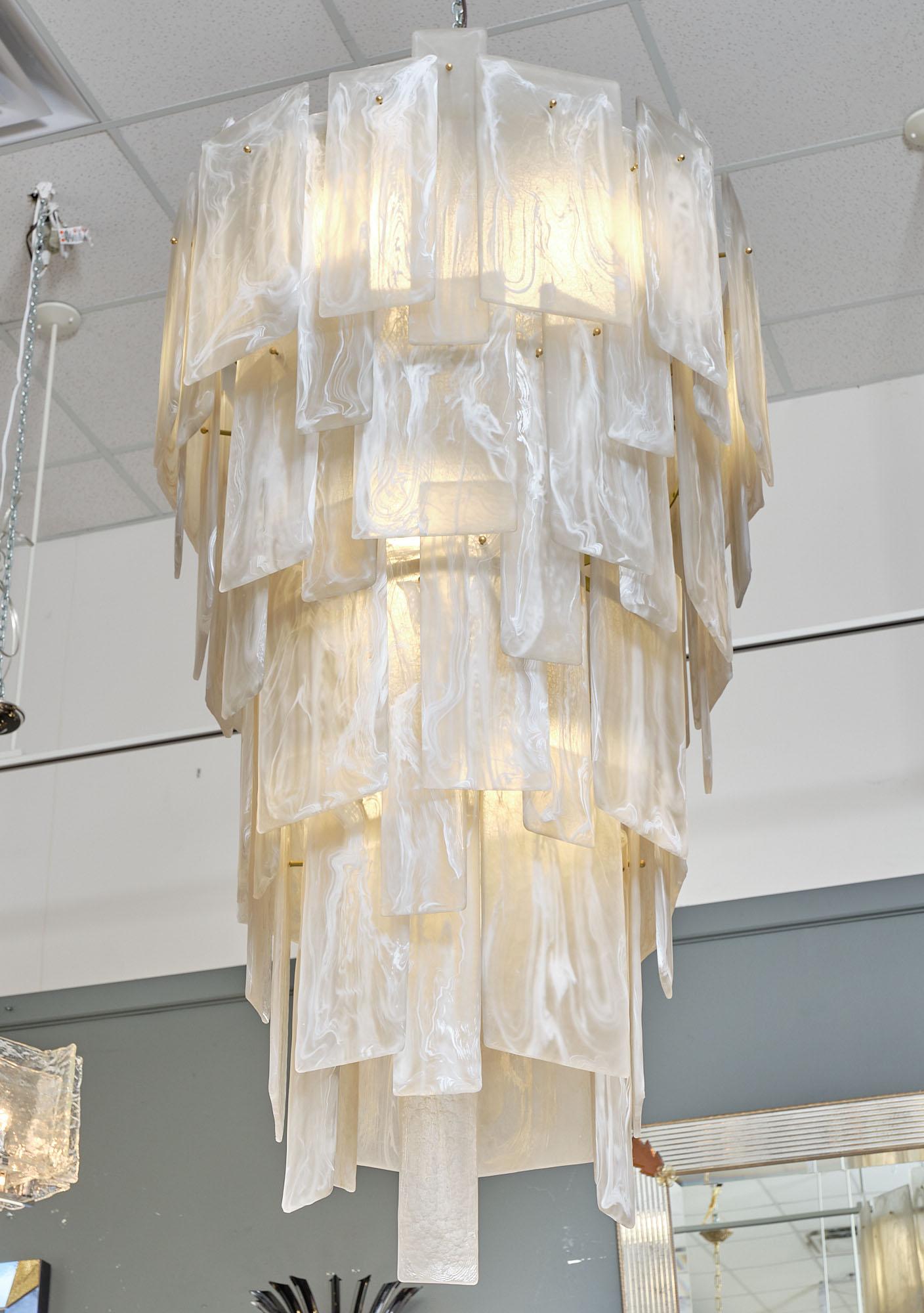Lampadario realizzato a mano da artigiani soffiatori di vetro a Murano, in Italia. I livelli a cascata presentano un bellissimo motivo alabastro nel vetro soffiato a mano. Il vetro alterna dimensioni e forme creando un design dinamico e unico.