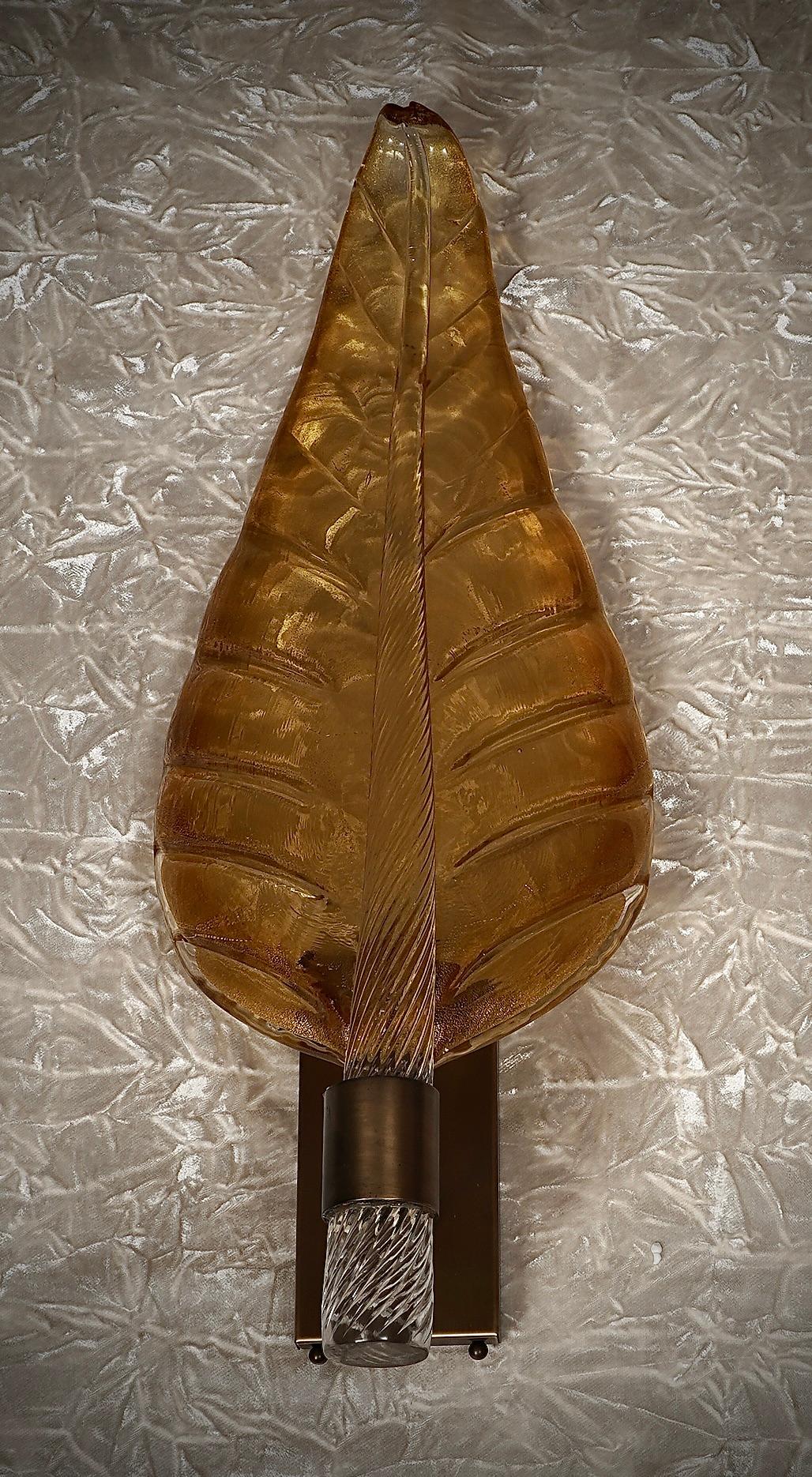 Majestuosa hoja de cristal de Murano de un maravilloso color ámbar, embellecida aún más por la base de latón satinado.

El aplique se compone de una estructura de latón que se fija a la pared con tacos y una gran hoja de cristal de Murano ámbar