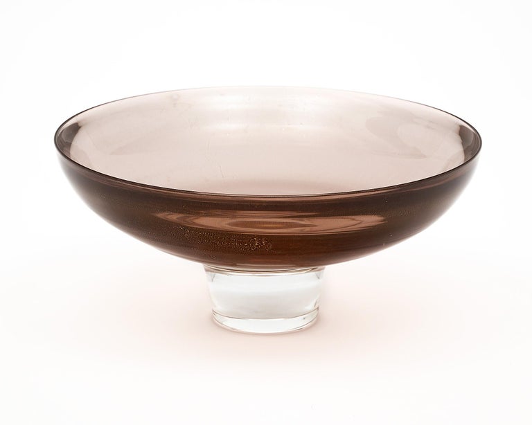 Bowl, Italian, from the island of Murano with a smoky amethyst color cup and clear base. This piece has 24 carat gold flecks or “avventurina” fused throughout the cup. It is hand crafted and signed by maestro Alberto Dona.