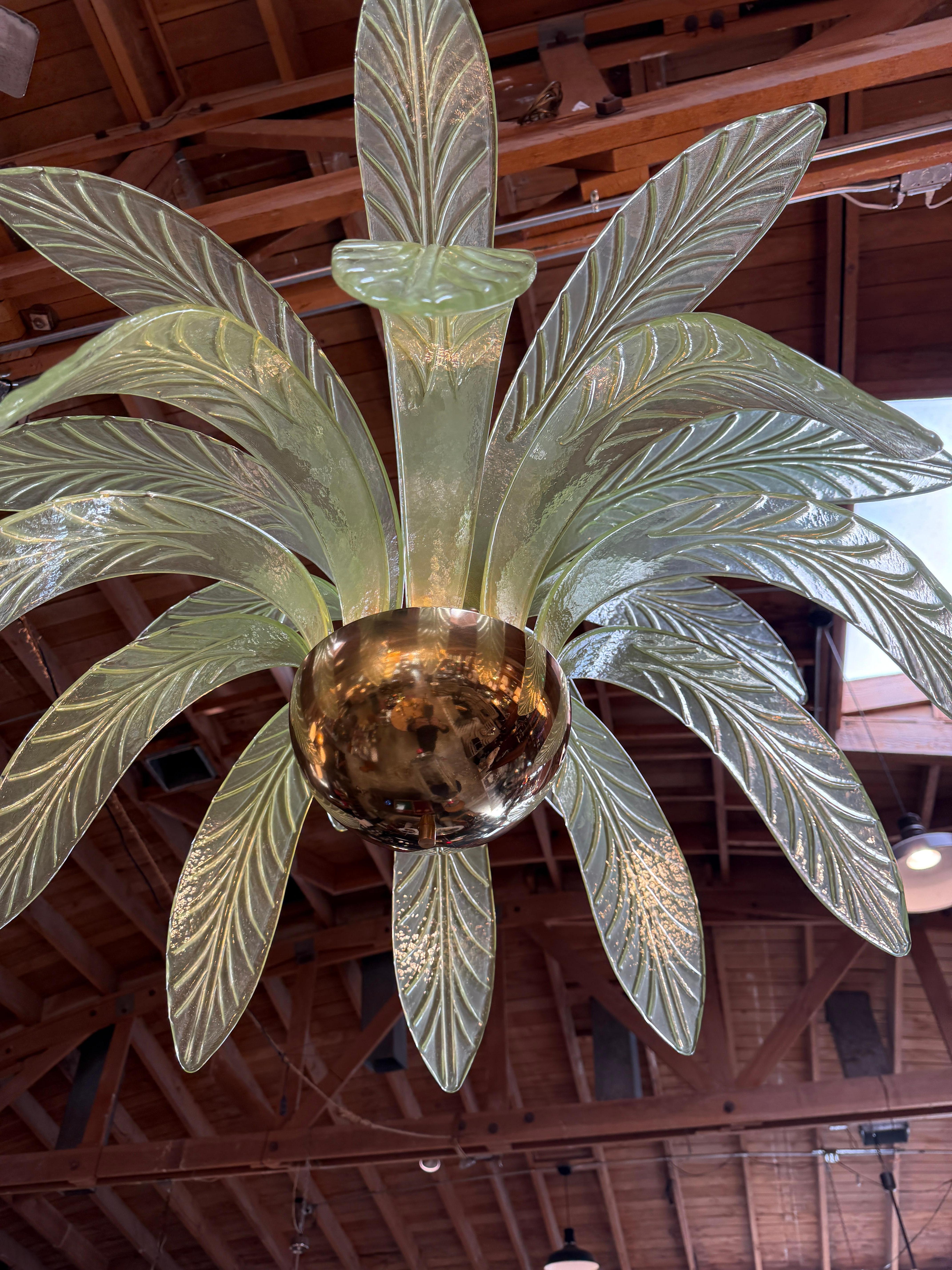 This is a stunning Murano chandelier featuring a distinctive design inspired by palm leaves. Its central structure consists of green glass leaves, delicately curved and detailed with intricate vein patterns, giving the piece a natural and tropical