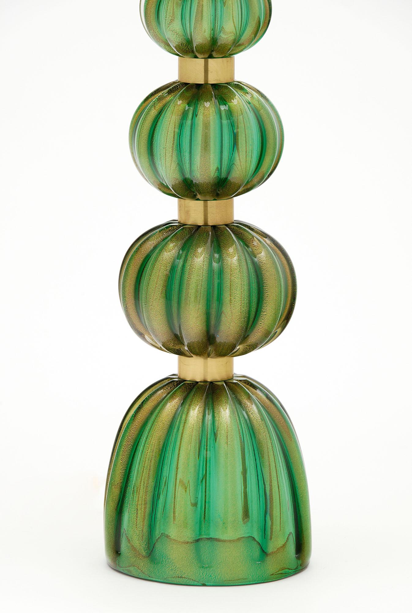 Pair of lamps from the island of Murano made of ridged green glass hand-blown and fused with 24 carat gold flecks in the “avventurina” technique. The spheres are supported by gilt brass rings. This pair has been newly wired to fit US standards. The