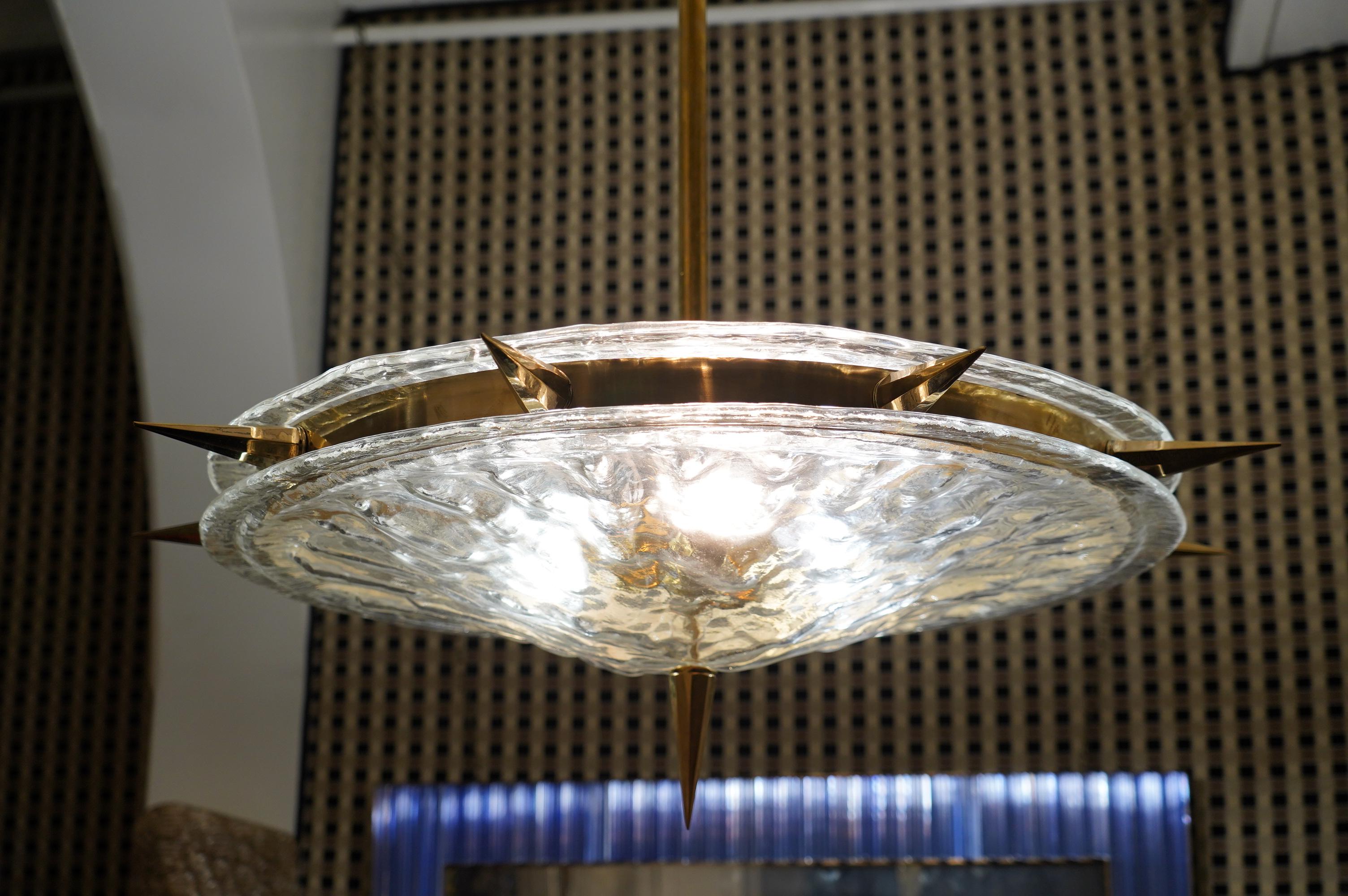 Superb chandelier for its characteristic round structure, unique design for the brass housing of the large transparent glass discs and brass castings in the shape of an inverted cone.

The chandelier has a very rare brass structure, formed by a