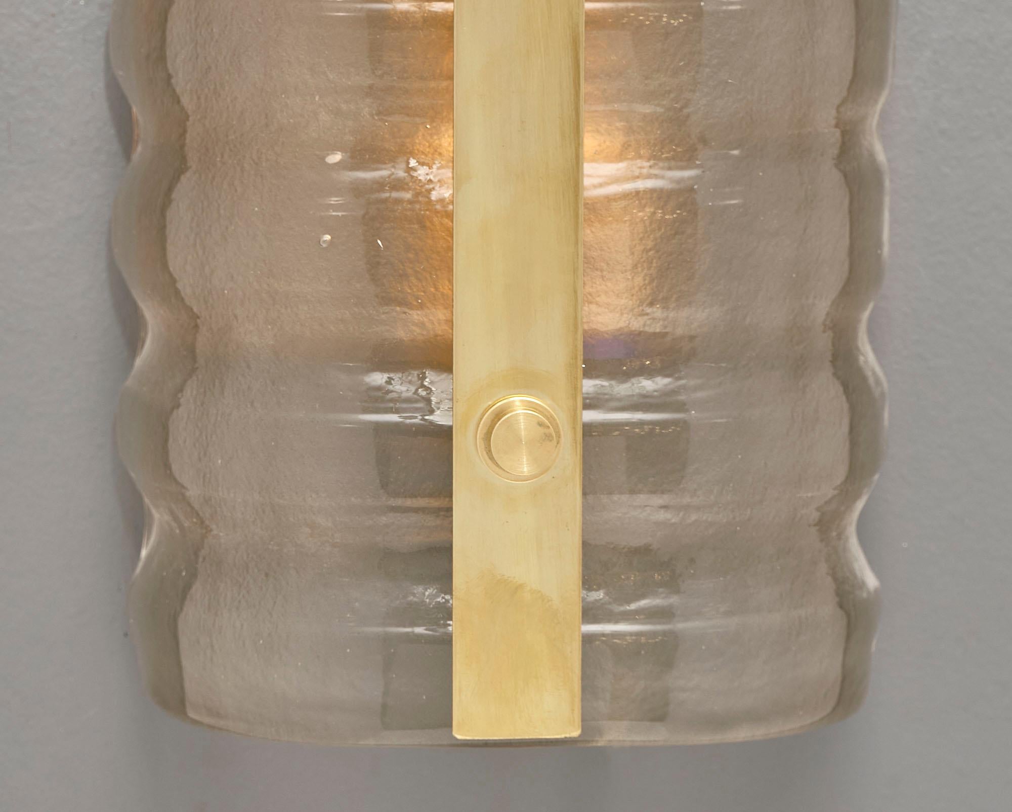 Murano glass and brass sconces with thick hand-blown undulating glass in a light amber color with a gilt brass trim. This pair has been newly wired to fit US standards.
This pair is currently located at our dealer's warehouse in Italy.
