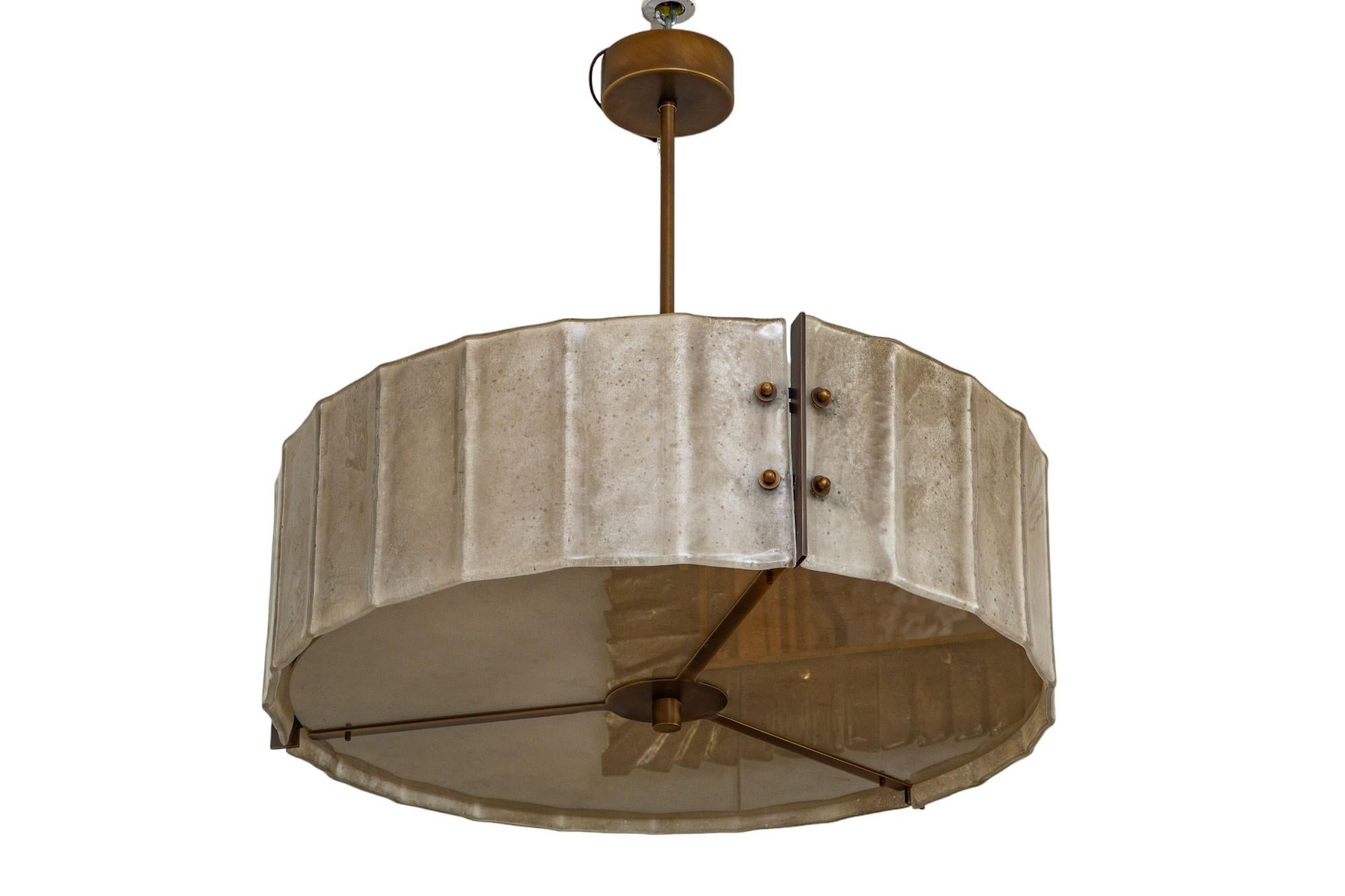Lampadario a tamburo in vetro scavo e bronzo di Murano, in stock
Tre vetri di Murano ondulati e sovrapposti che formano un lampadario a tamburo scultoreo.
Cinque lampadine a base regolare, 
Il peso totale è di 95 libbre.
Raccordi con finitura