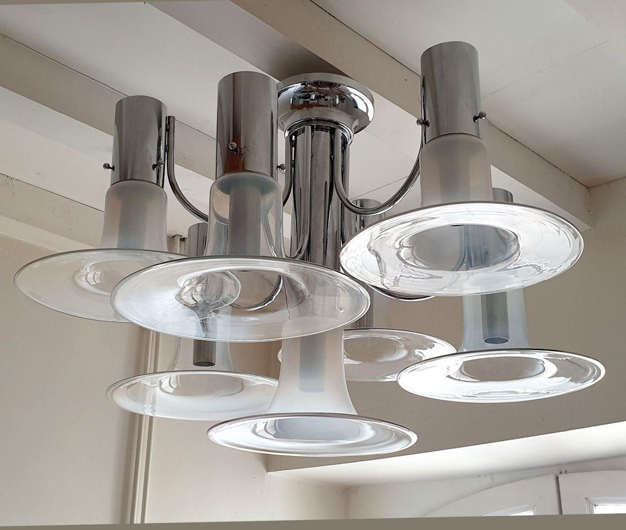 Grande lampadario o lampada a incasso in vetro di Murano e cromo, in stile Mid Century Modern, attribuito a Carlo Nason, per Mazzega Murano Italia anni '70.
Questo lampadario moderno vintage è composto da montature cromate e 7 paralumi in vetro di
