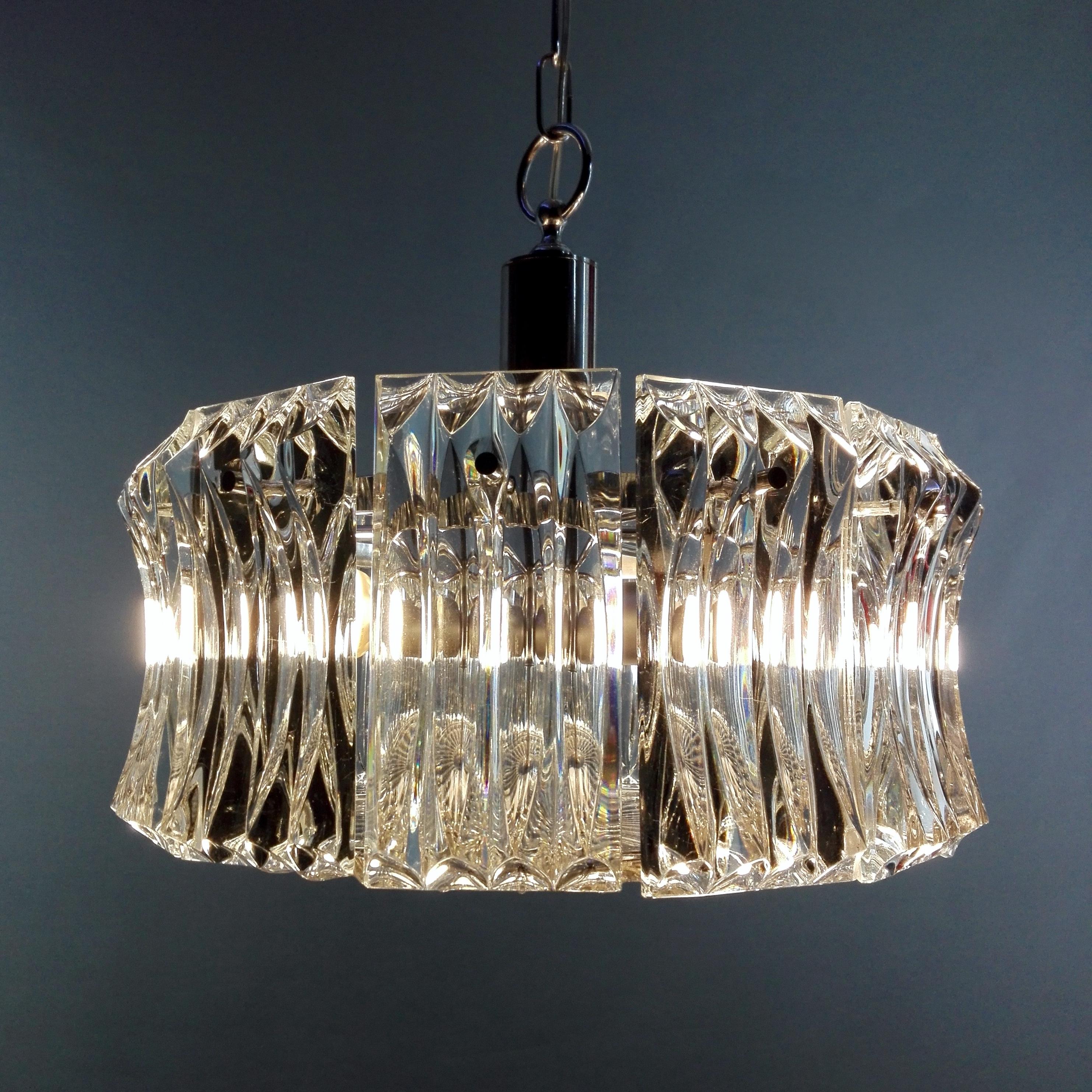 Wonderful Italian 60s three-light chandelier, design Paolo Venini attributable. The frame supports 12 solid clear glass worked plates, fixed to a circular chrome structure. Another solid round worked glass plate is fixed at the bottom to filter the