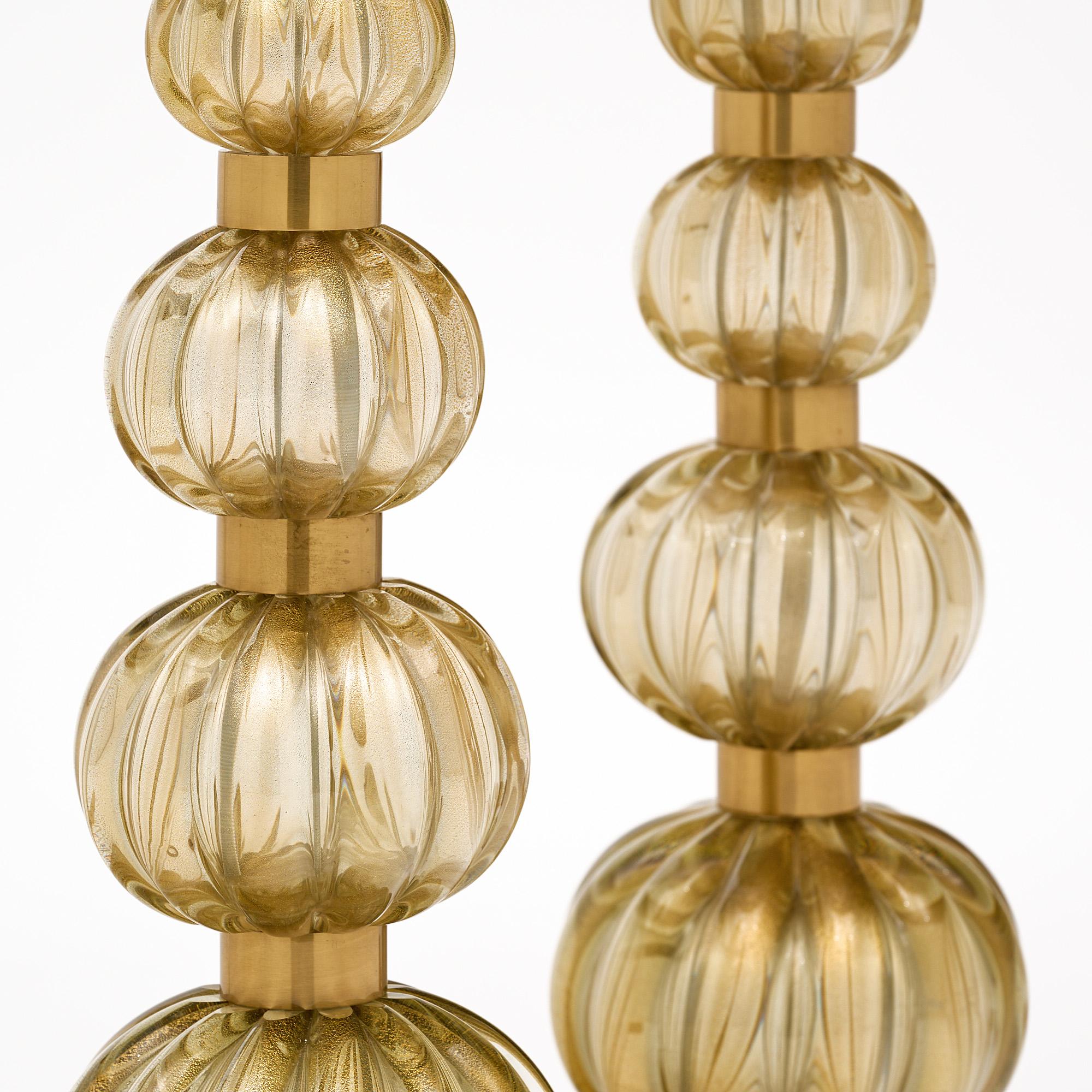 Pair of Murano glass lamps, from the island of Murano next to Venice, Italy. The smoked glass ridged spheres were crafted in the Avventurina technique with 24 carat gold powder fused within the blown glass components. These glass lamps feature five
