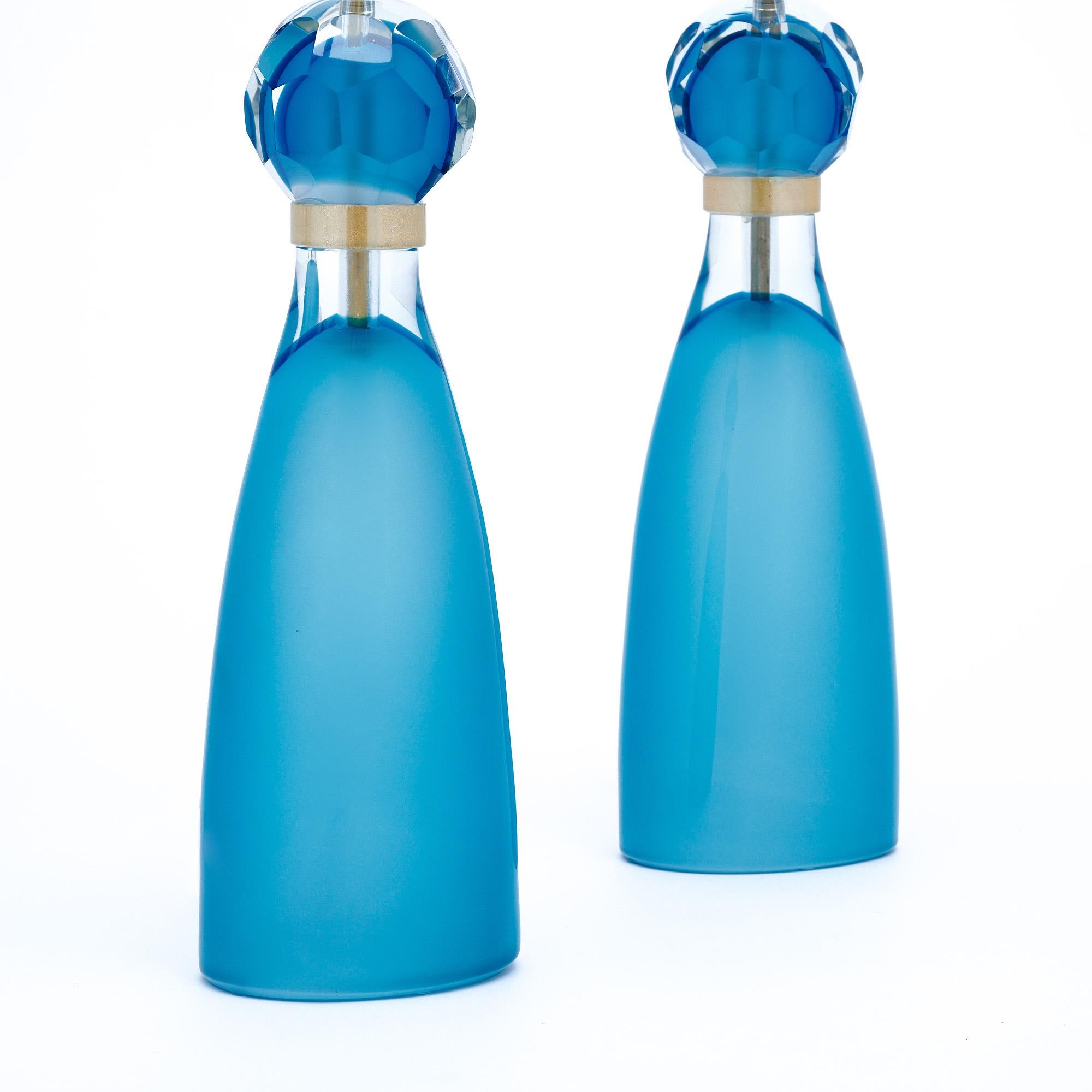 Pair of Italian hand-blown Murano glass table lamps in a polished aqua blue glass fading to clear just below 23-carat gold flecked rings. At once formal and playful, these sleek lights are sure to take your space to the next level. We were drawn to