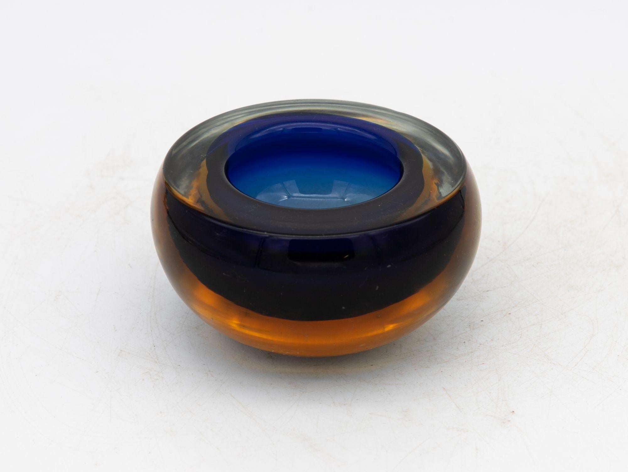 Crafted in the vibrant spirit of the 1960s, this Murano glass ashtray exudes timeless charm. With its square shape and gently rounded corners, the thick glass construction boasts both sturdiness and elegance. The color palette, a gradient of deep