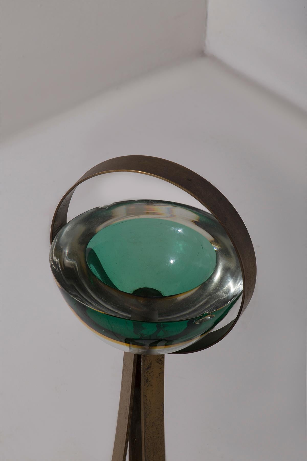 This elegant 1950s ashtray evokes the design of Fontana Arte, combining stylistic innovation and high-quality materials. The brass structure, with a solid pedestal and integrated handle, harmonizes with the hand-blown Murano glass bowl, renowned for