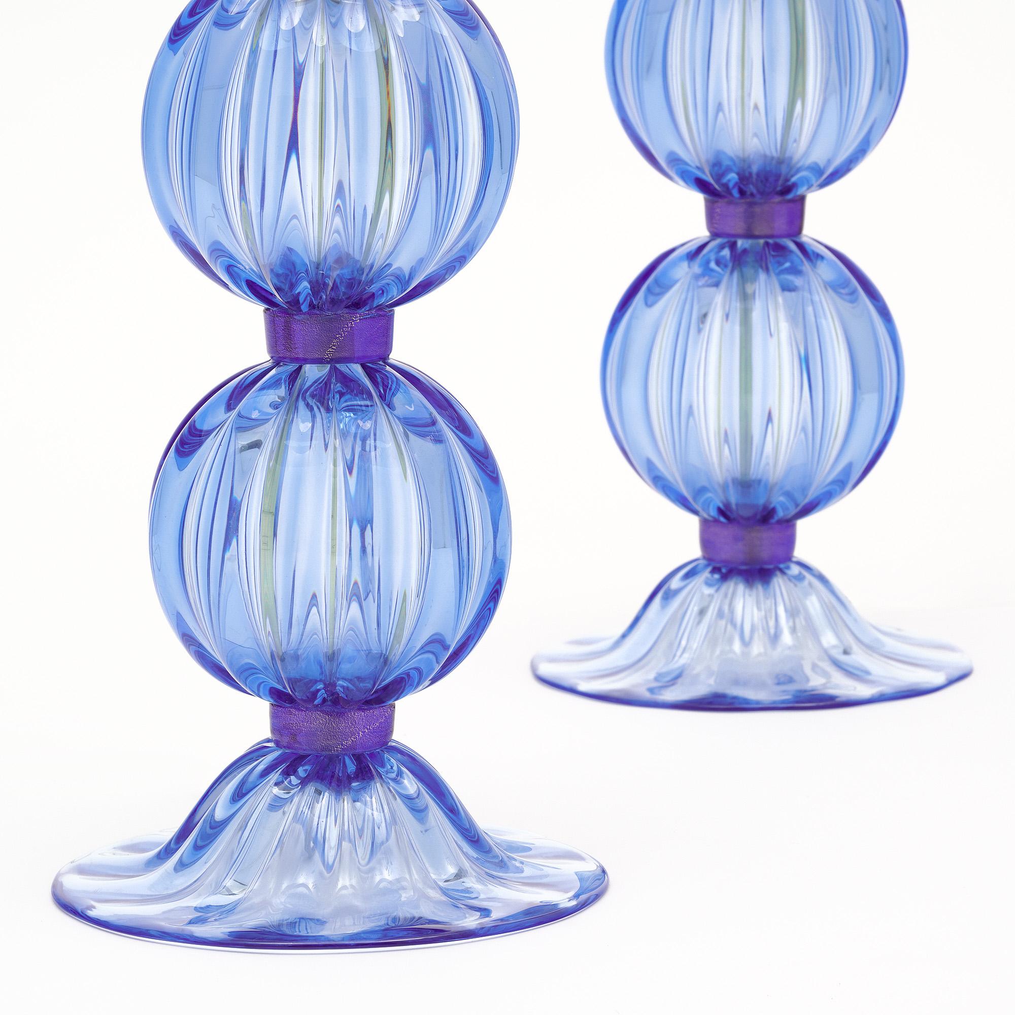 Pair of lamps made of hand-blown glass from the island of Murano outside of Venice, Italy. The lamps feature two blown ridged glass spheres in a striking blue tone. The glass is held together with purple glass rings. They have been newly wired to