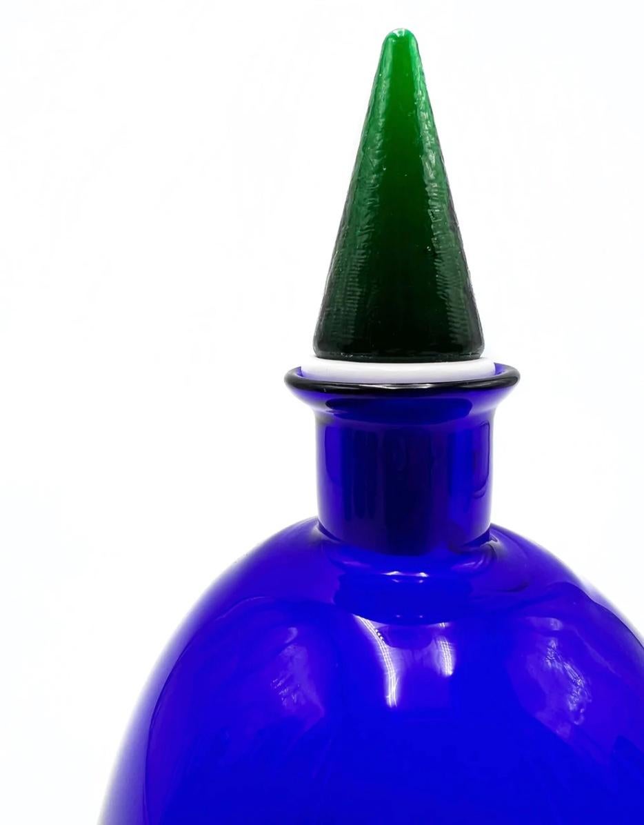 Blue Murano glass bottle and green triangular cap, made by Carlo Moretti in the 1980s

Measures: Ø cm 11 h cm 21,5.