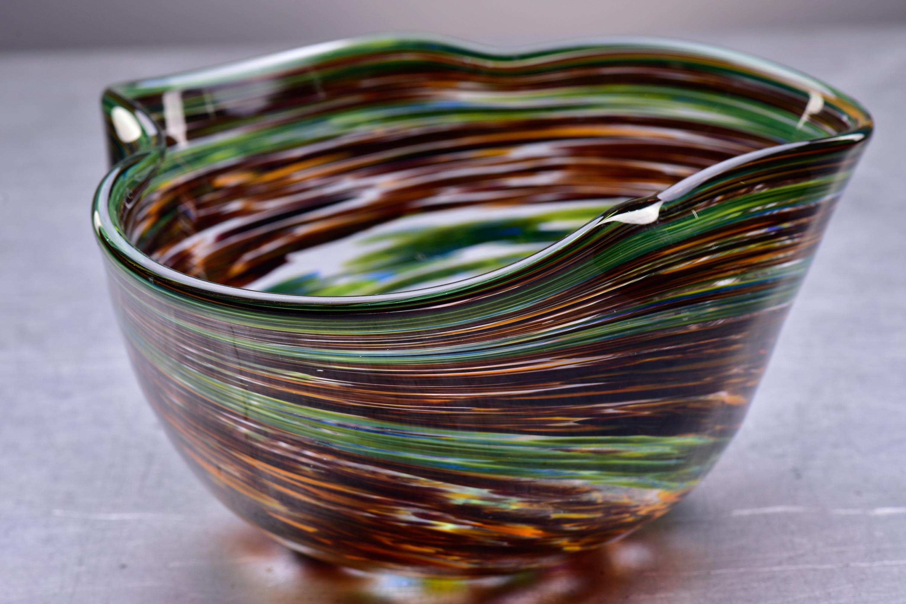Circa 2020 Murano glass bowl with amorphous shape and pinched rim in rich green and earth tone swirls. Unsigned. New condition with no flaws found.