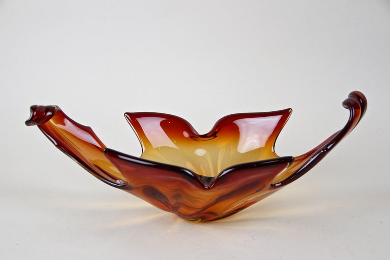 Beautiful, highly decorative Murano glass bowl out of the renown workshops in Italy from around 1960/70. Coming in lovely red and orange tones, this large glass bowl or centerpiece impresses with its unusual shape and amazing design. It can be used