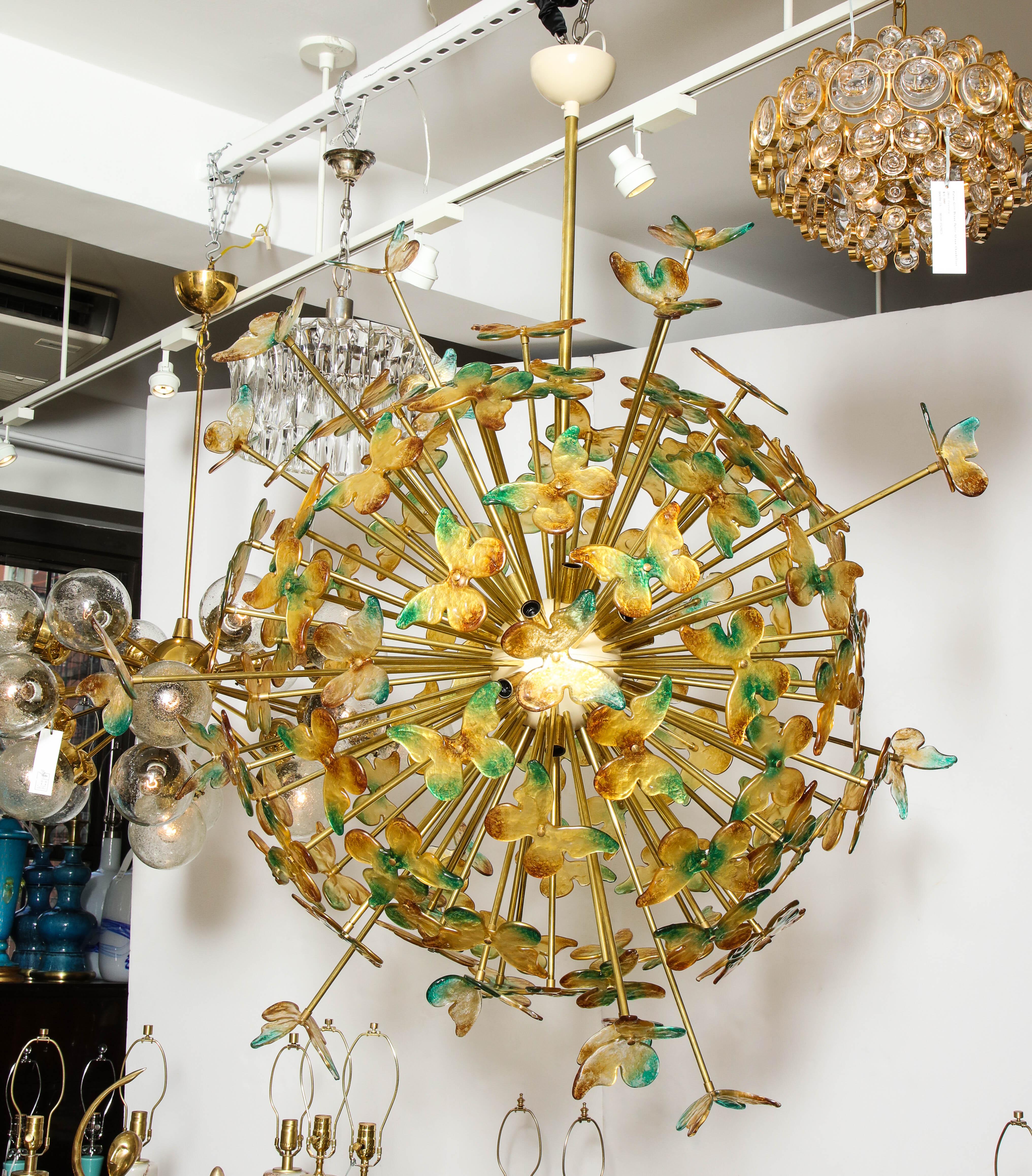 Large scale majestic sputnik chandelier featuring a brass armature and Murano glass butterflies in tones of green, gold and ambers. Two different body styles of the butterflies creates an effect of the butterflies in flight. 18 light sources.