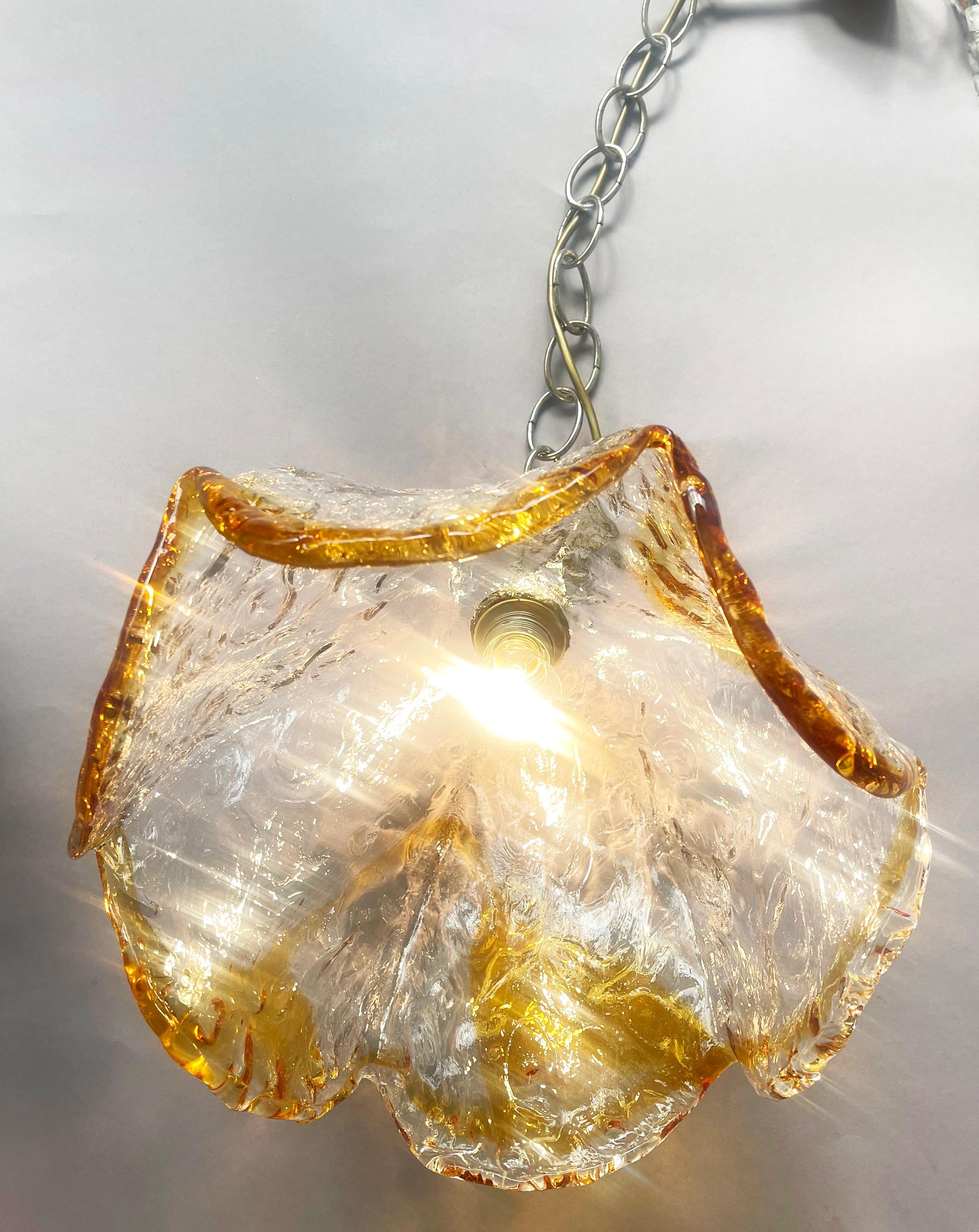 Pendente in vetro di Murano lavorato a mano dal produttore tedesco di illuminazione di metà secolo Honsel.
Un classico del design tedesco degli anni '70 a forma di calice, in vetro trasparente e dettagli ambrati che riflettono magnificamente la